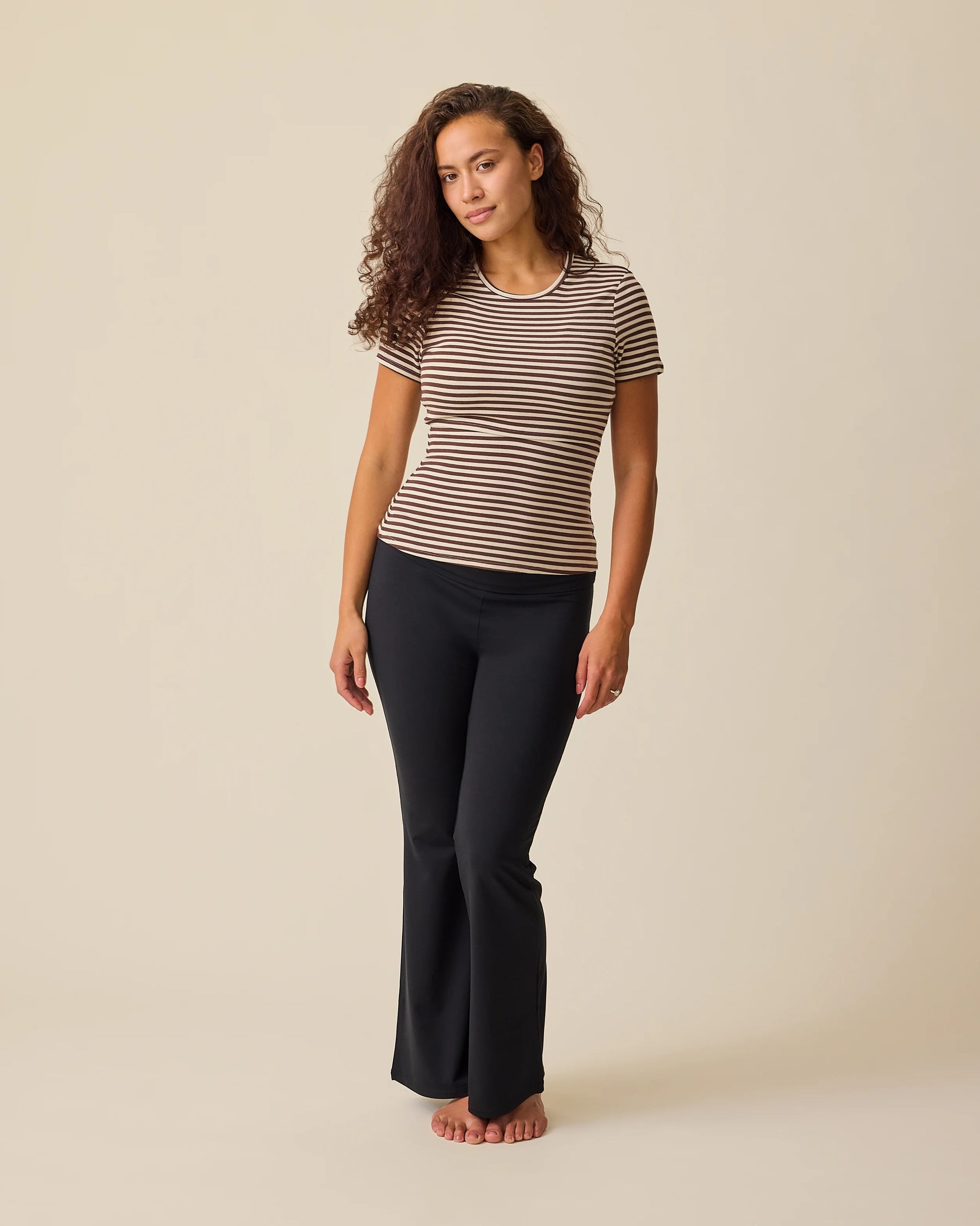 Model is wearing the Ribbed Bamboo Crew Neck Nursing T-shirt in Chocolate & Ivory Stripe on a beige background.