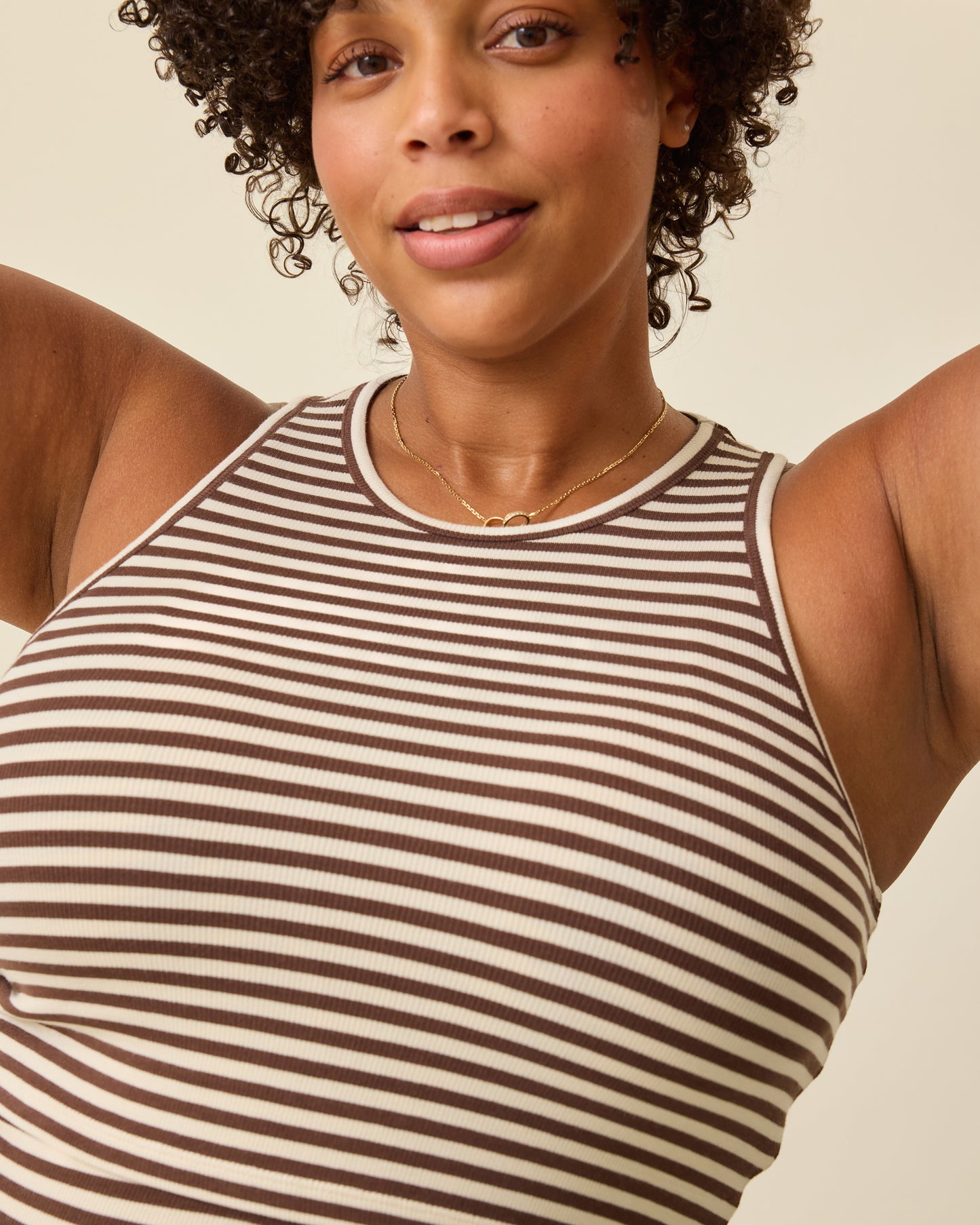 Close up of model wearing Ribbed Bamboo Racerback Nursing Tank in Chocolate & Ivory Stripe on a beige background. 