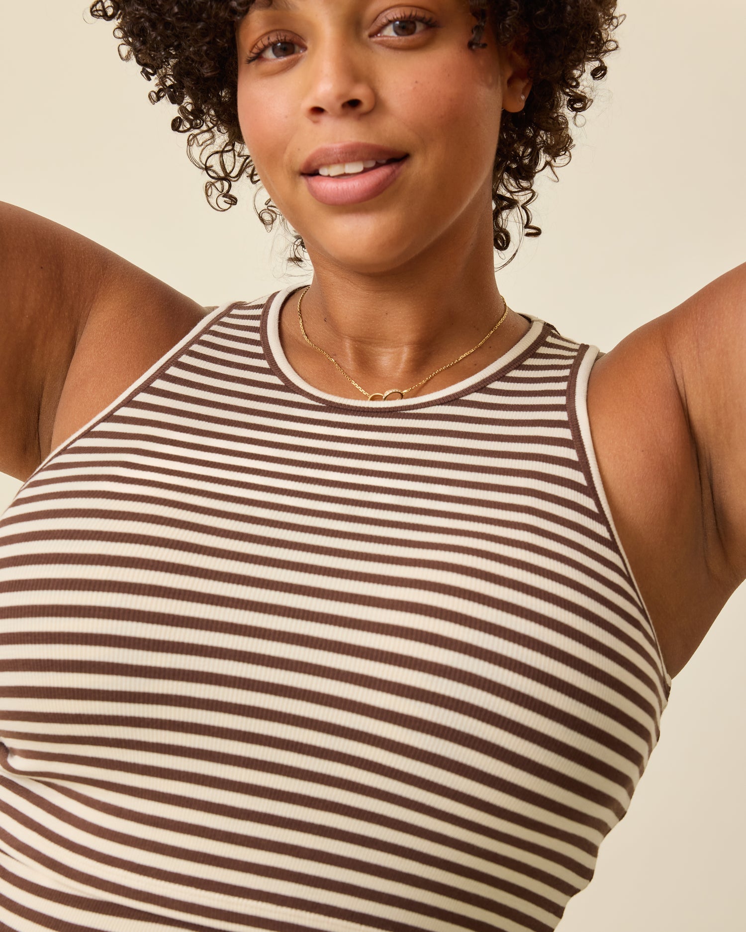 Close up of model wearing Ribbed Bamboo Racerback Nursing Tank in Chocolate & Ivory Stripe on a beige background. 