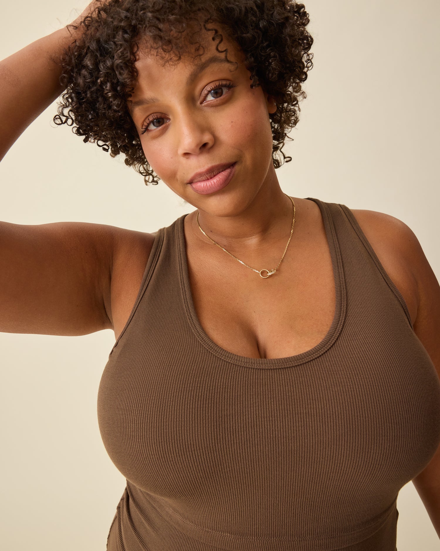 Close up of model wearing Ribbed Bamboo Scoop Neck Nursing Tank in Chocolate on a beige background. 