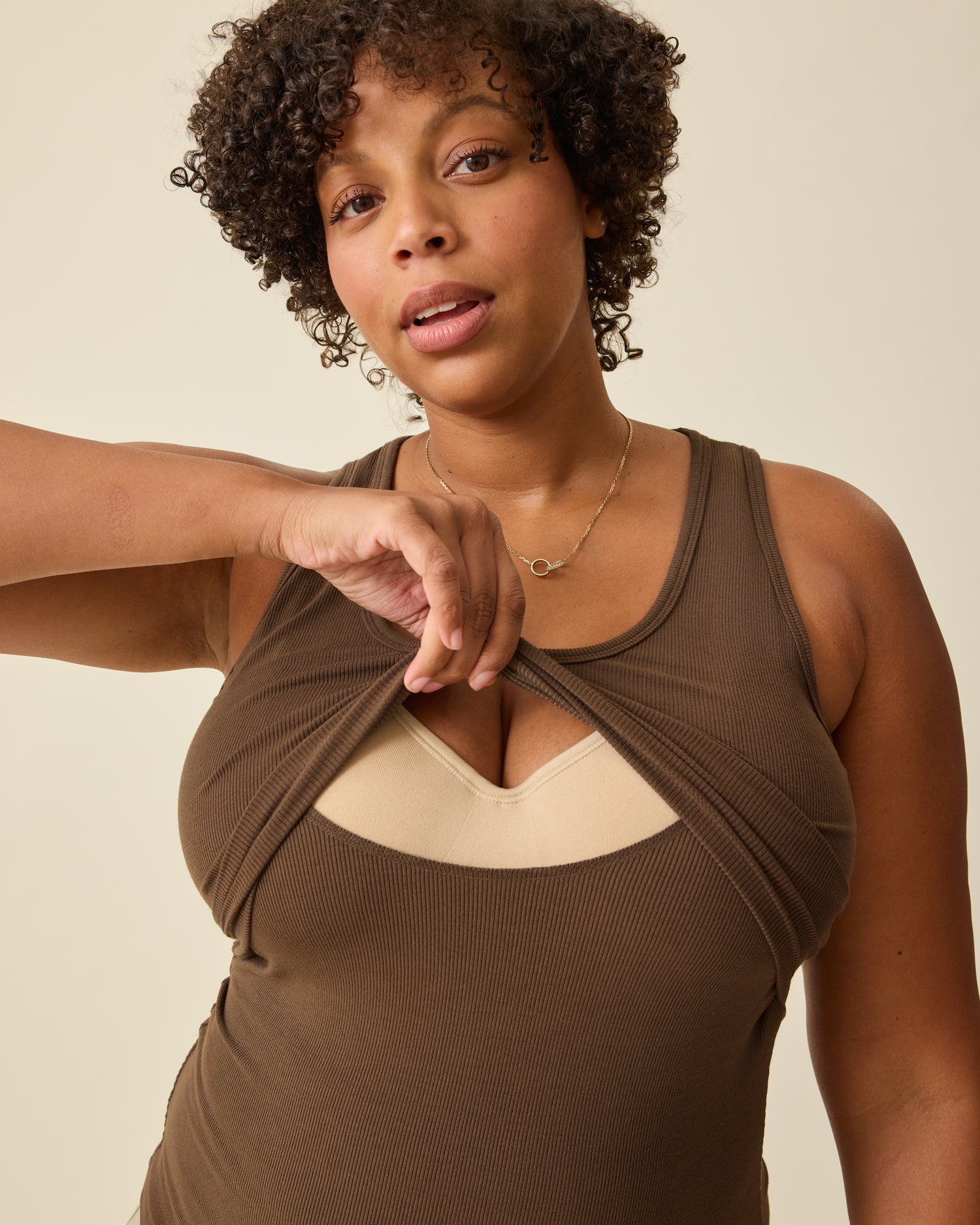 Model is lifting breastfeeding panel on Ribbed Bamboo Scoop Neck Nursing Tank in Chocolate on a beige background. 