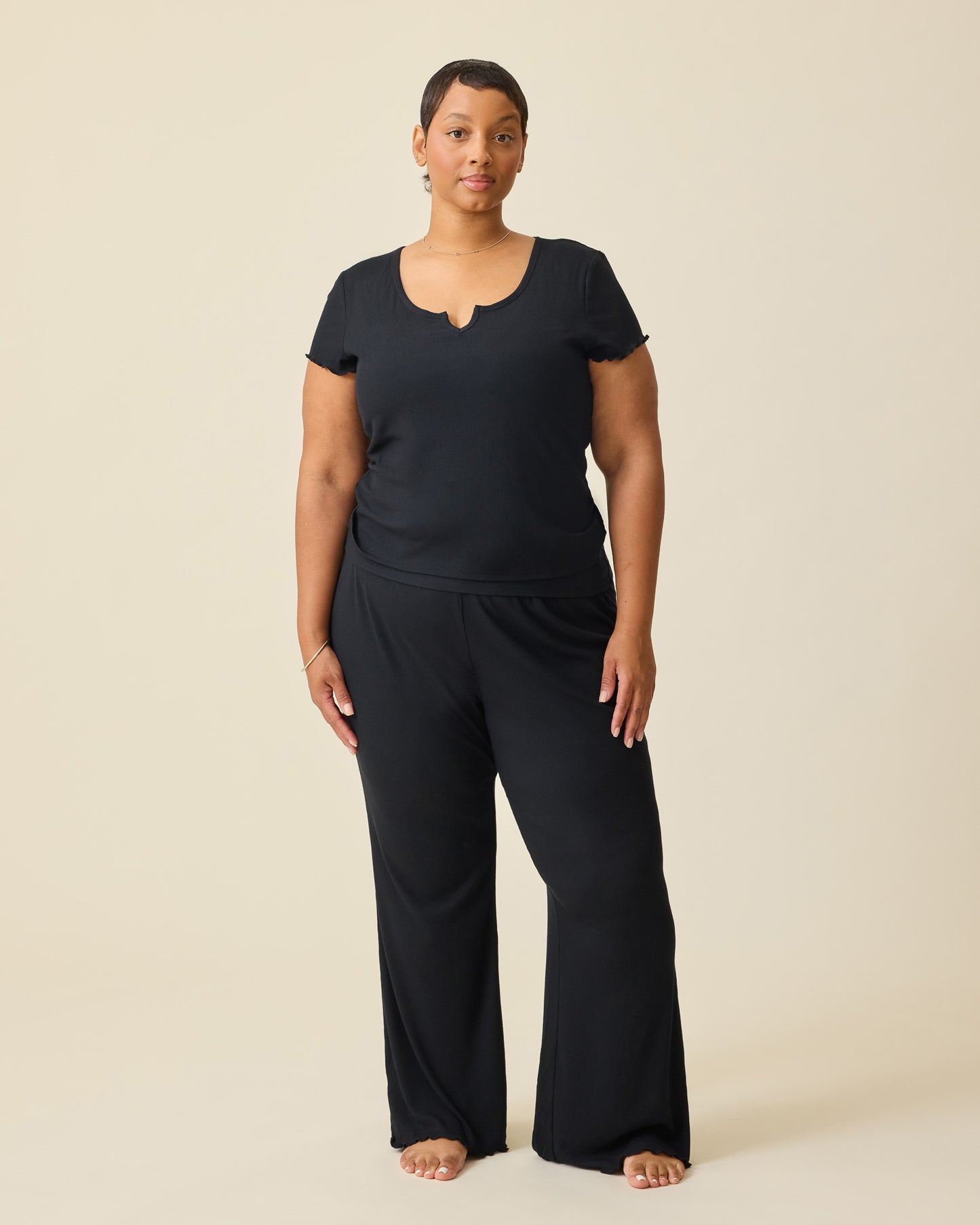 Model wearing Ribbed Modal Lounge Pant in Black and Ribbed Modal Notched Nursing T-shirt in Black on a beige background.@model_info:Brittany is 5'5" and wearing a 1X.