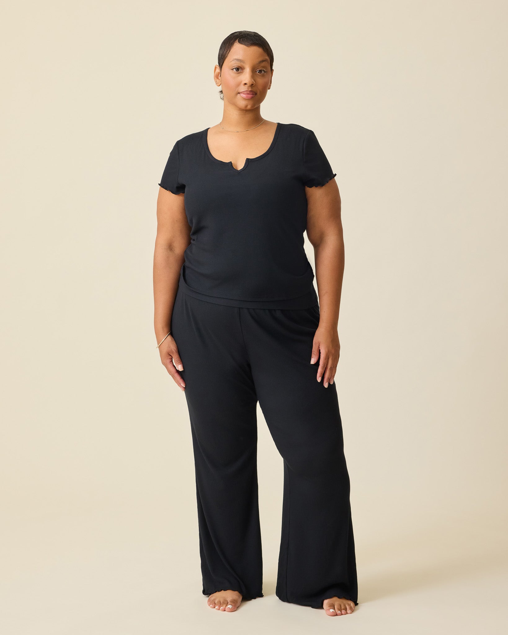 Model wearing Ribbed Modal Lounge Pant in Black and Ribbed Modal Notched Nursing T-shirt in Black on a beige background.@model_info:Brittany is 5'5" and wearing a 1X.
