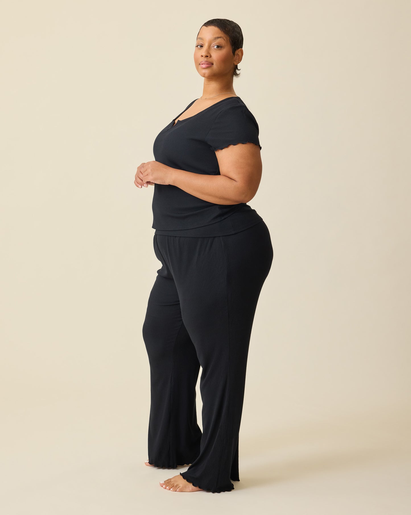 Side view of model wearing Ribbed Modal Lounge Pant in Black and Ribbed Modal Notched Nursing T-shirt in Black on a beige background.@model_info:Brittany is 5'5" and wearing a 1X.