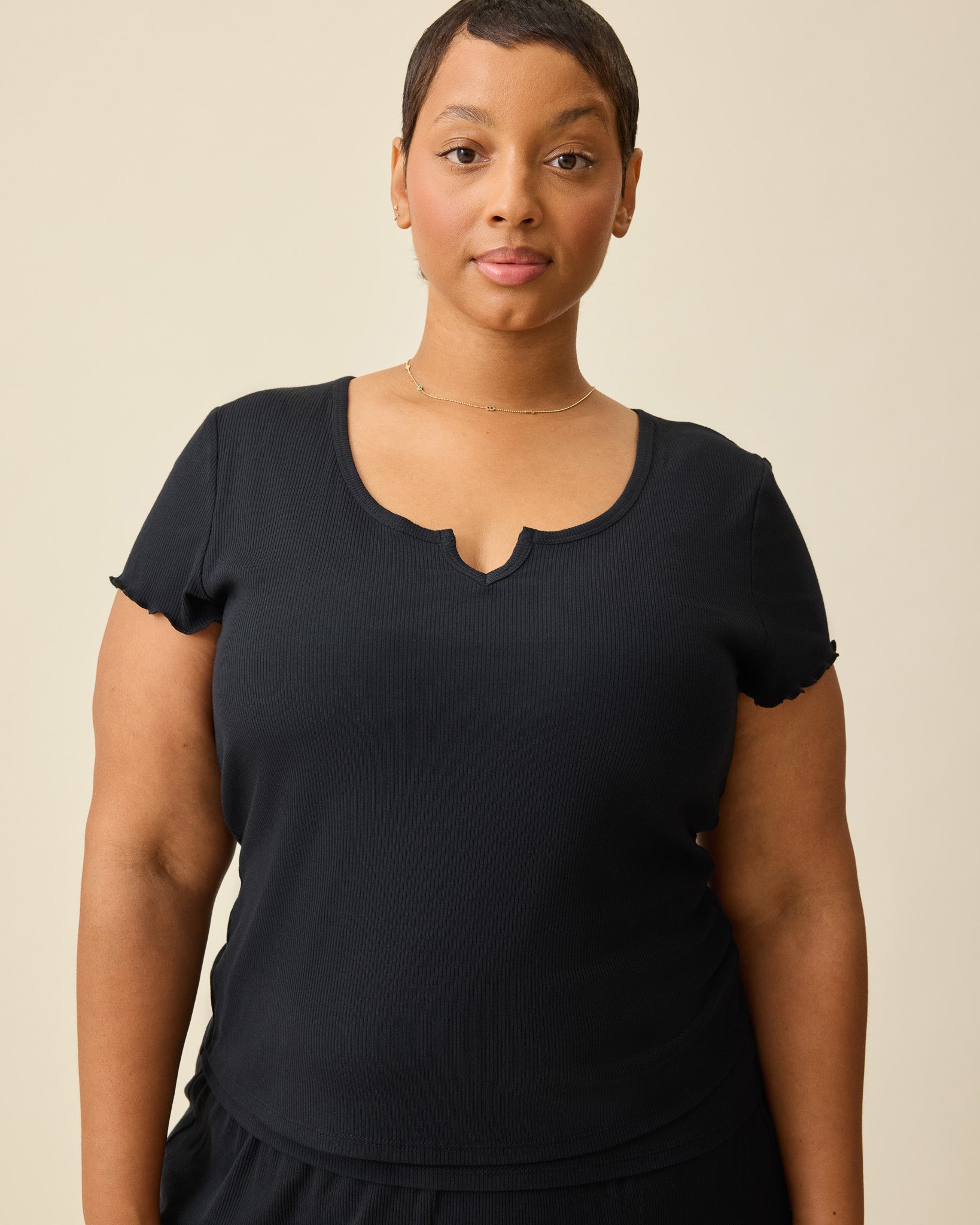 Model is wearing Ribbed Modal Notched Nursing T-shirt in Black on a beige background. 