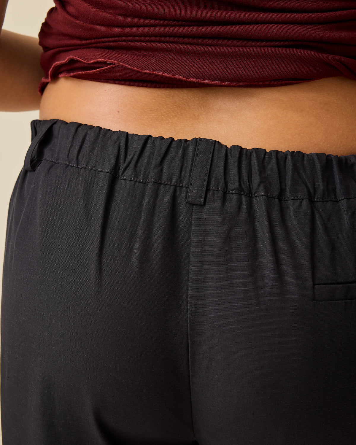 Close up of back view of model wearing Maternity & Postpartum Wide Leg Trouser in Black on a beige background.