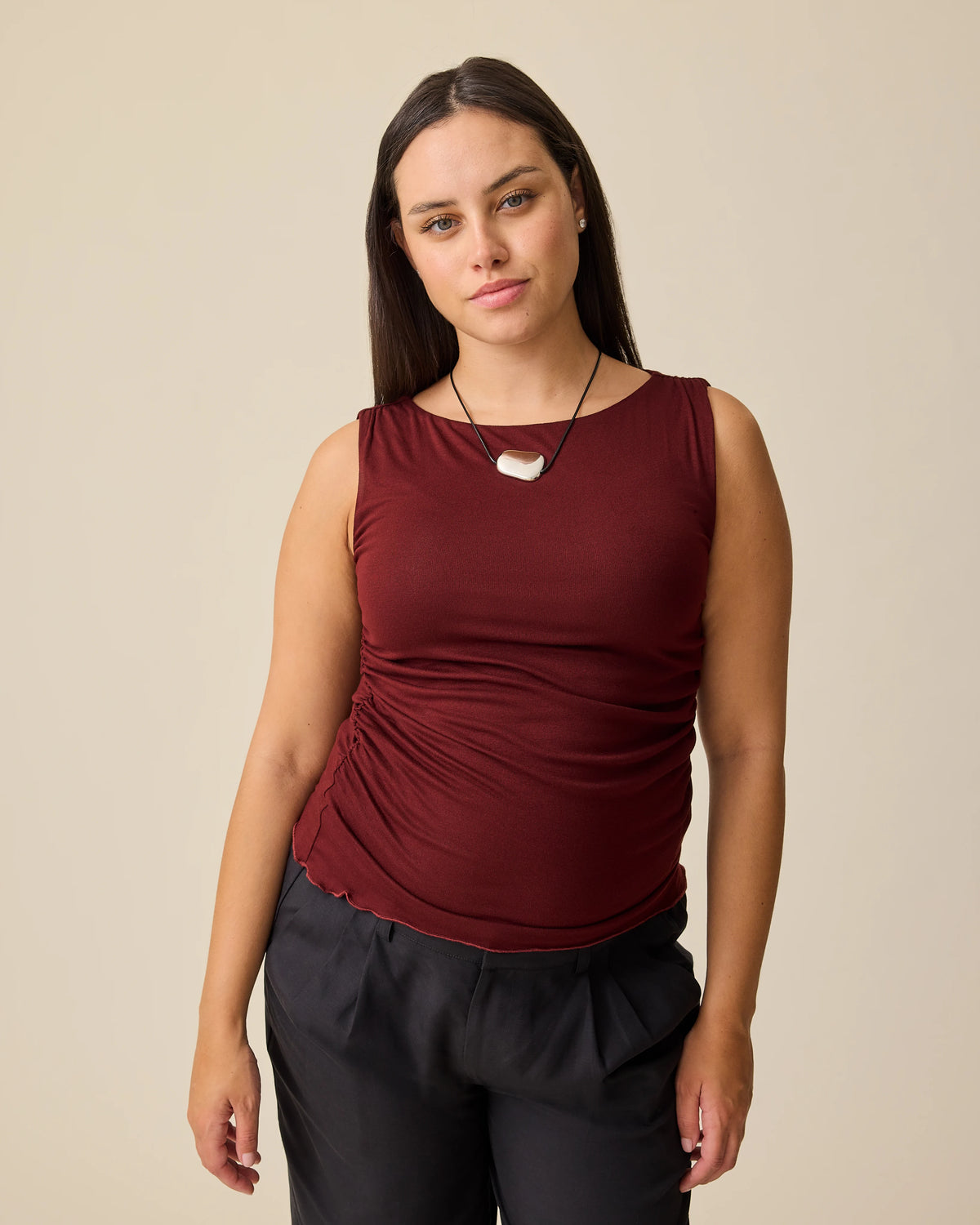Model is wearing Ruched Maternity Sleeveless Top in Burgundy and Maternity & Postpartum Wide Leg Trouser in Black on a beige background. @model_info:Brianna is wearing a Medium.