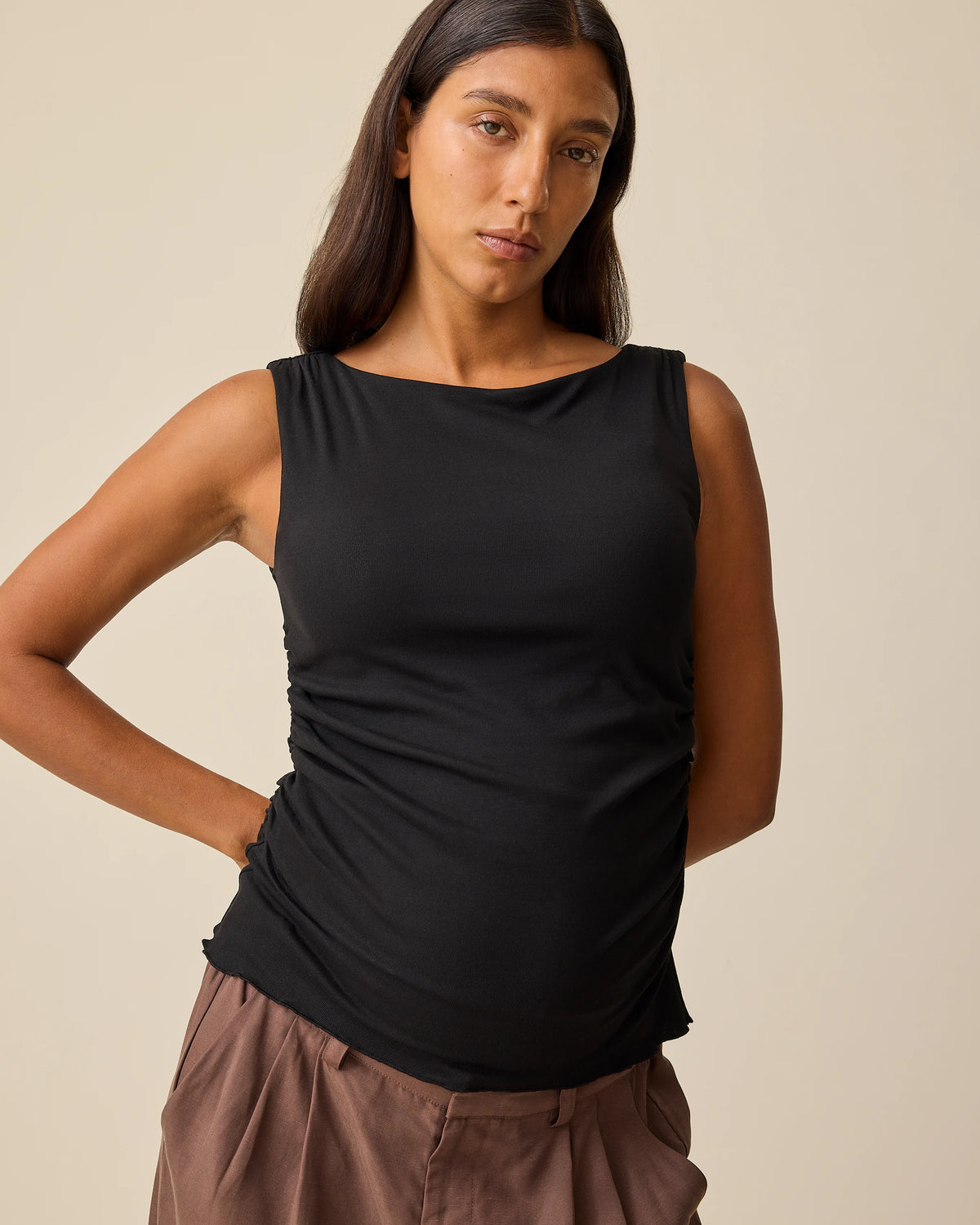 Model is wearing Maternity & Postpartum Wide Leg Trouser in Brown and Ruched Maternity Sleeveless Top in Black on a beige background.@model_info:Hayley is wearing a Small.
