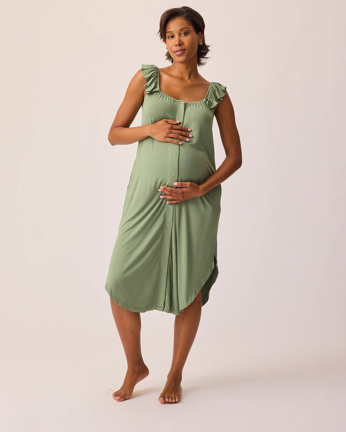 Model is wearing Ruffle Strap Labor & Delivery Gown in Sage on a beige background. @model_info:Ale is 5'9" and wearing a M/L.