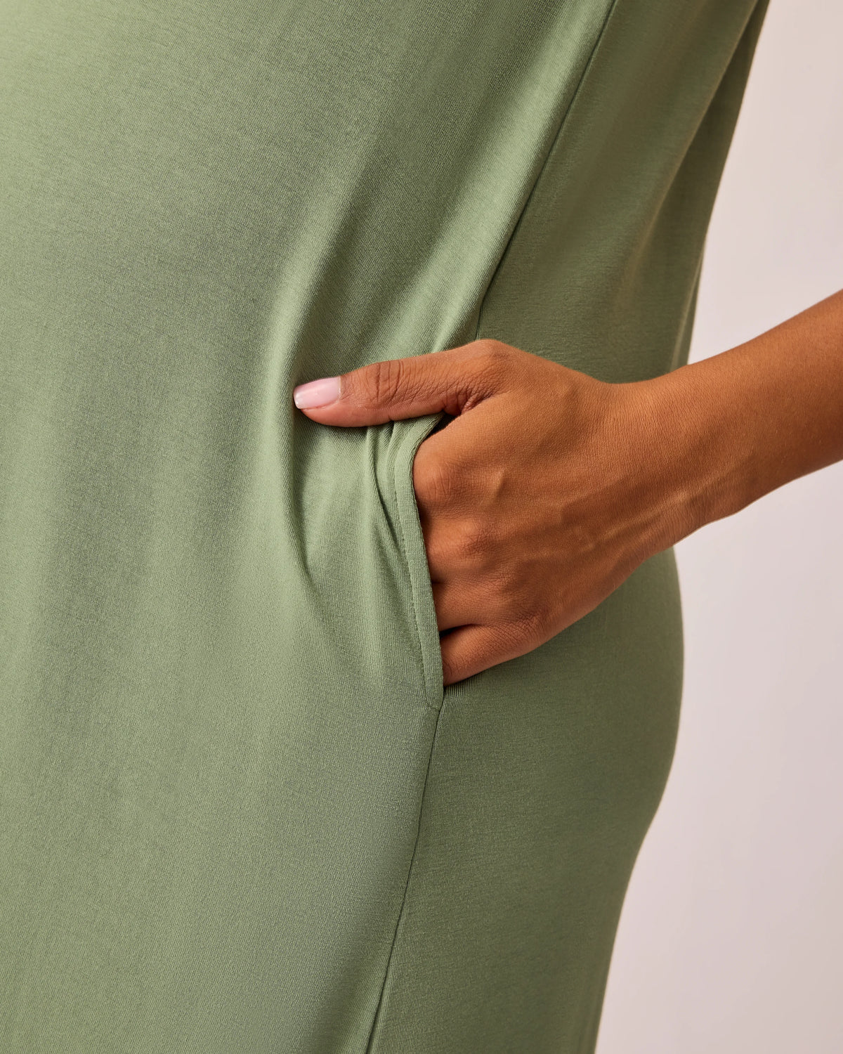 Close up of the pockets of the Ruffle Strap Labor & Delivery Gown in Sage on a beige background.