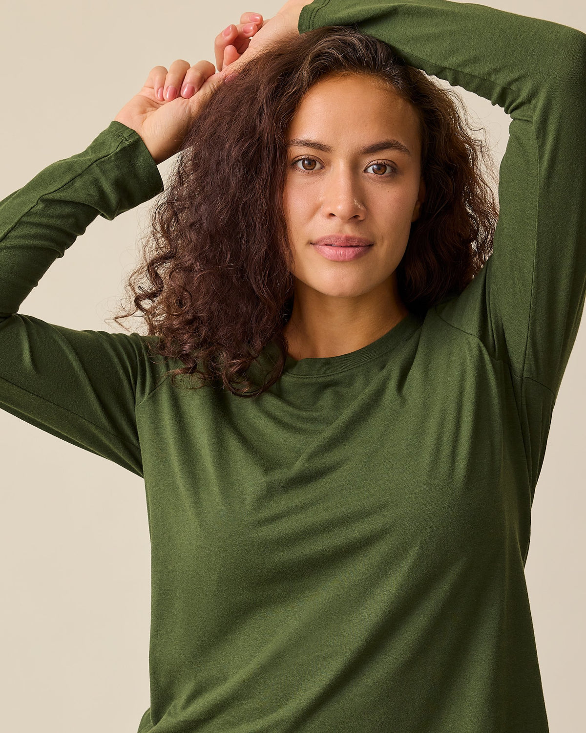 Close up of model wearing Modal Long Sleeve Nursing T-shirt in Deep Olive on a beige background.