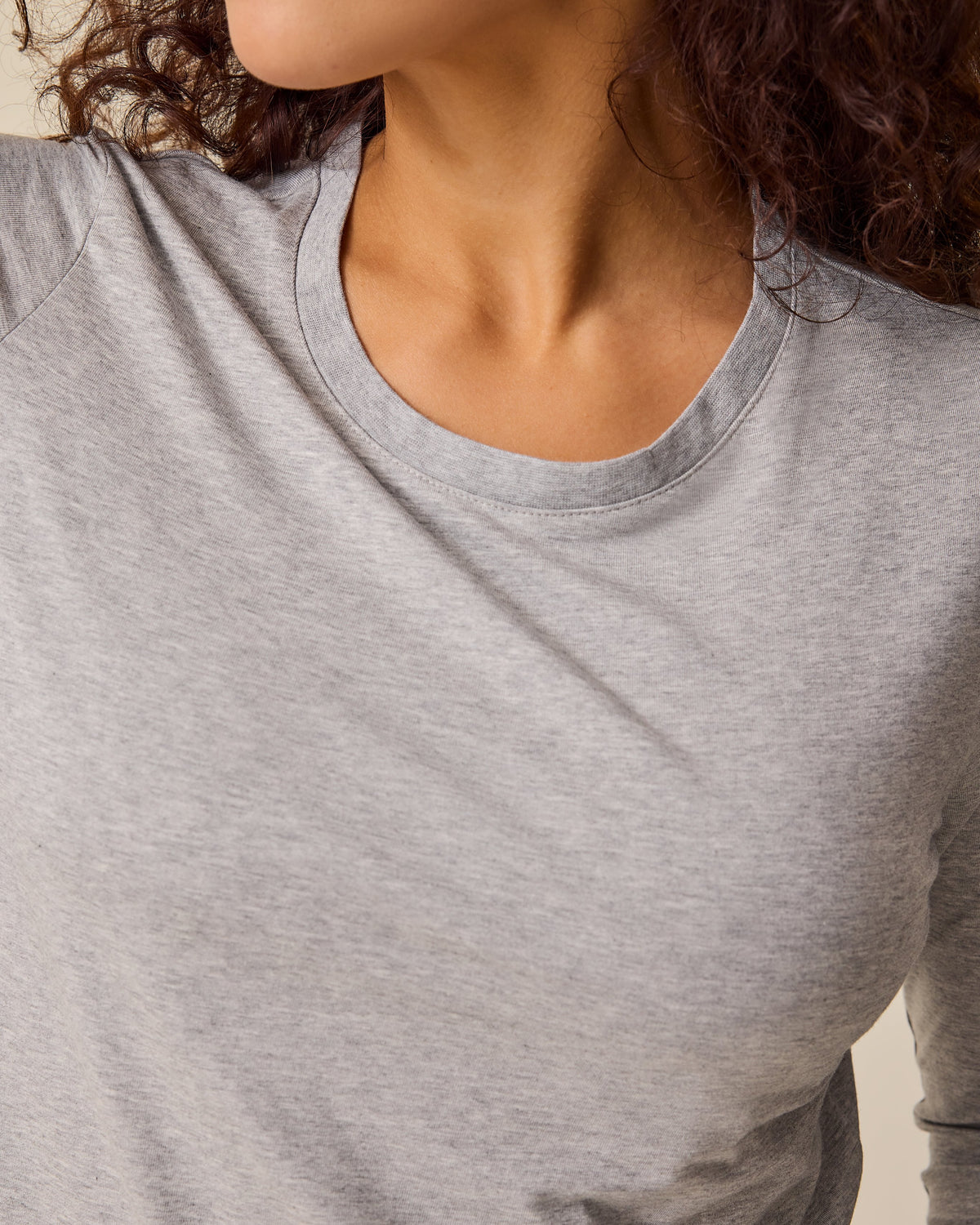 Close up of the neckline of the Modal Long Sleeve Nursing T-shirt in Grey Heather on a beige background.