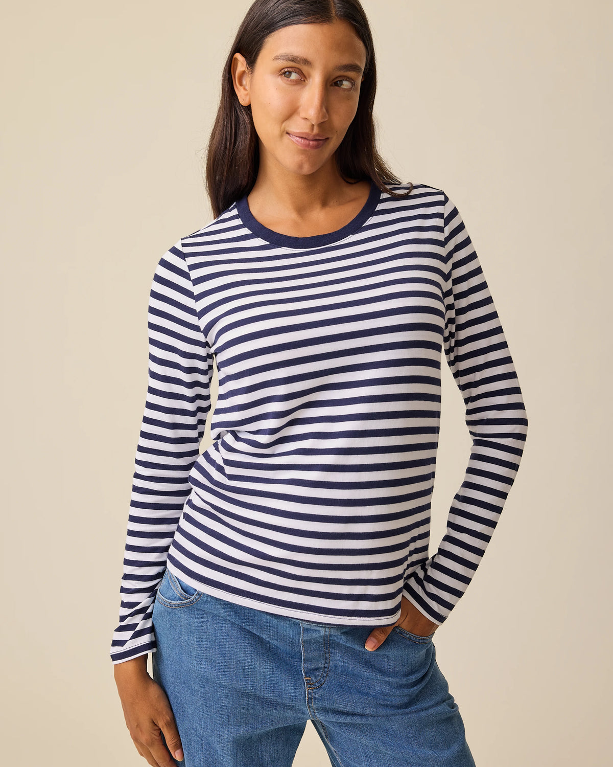 Model is wearing Modal Long Sleeve Nursing T-shirt in Navy & White Stripe and Wide Leg Maternity & Postpartum Jean in Medium Wash on a beige background.@model_info:Hayley is wearing a Small.