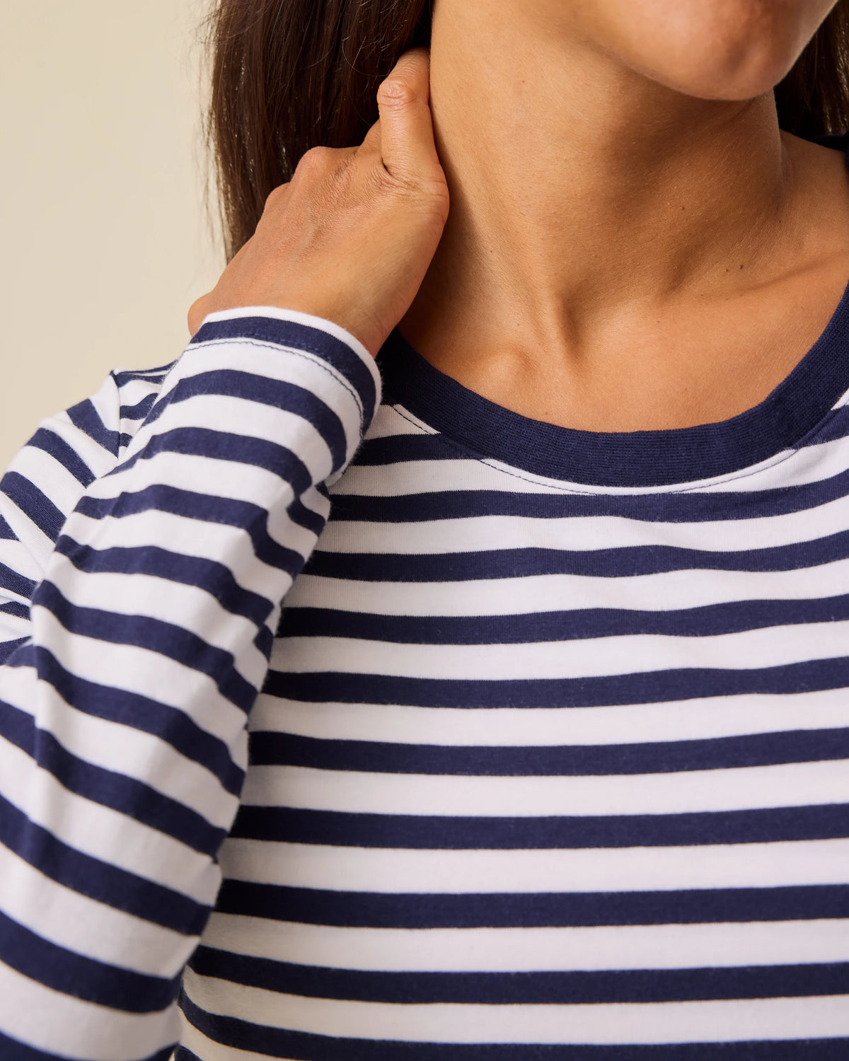 Close up of model wearing  Modal Long Sleeve Nursing T-shirt in Navy & White Stripe on a beige background.