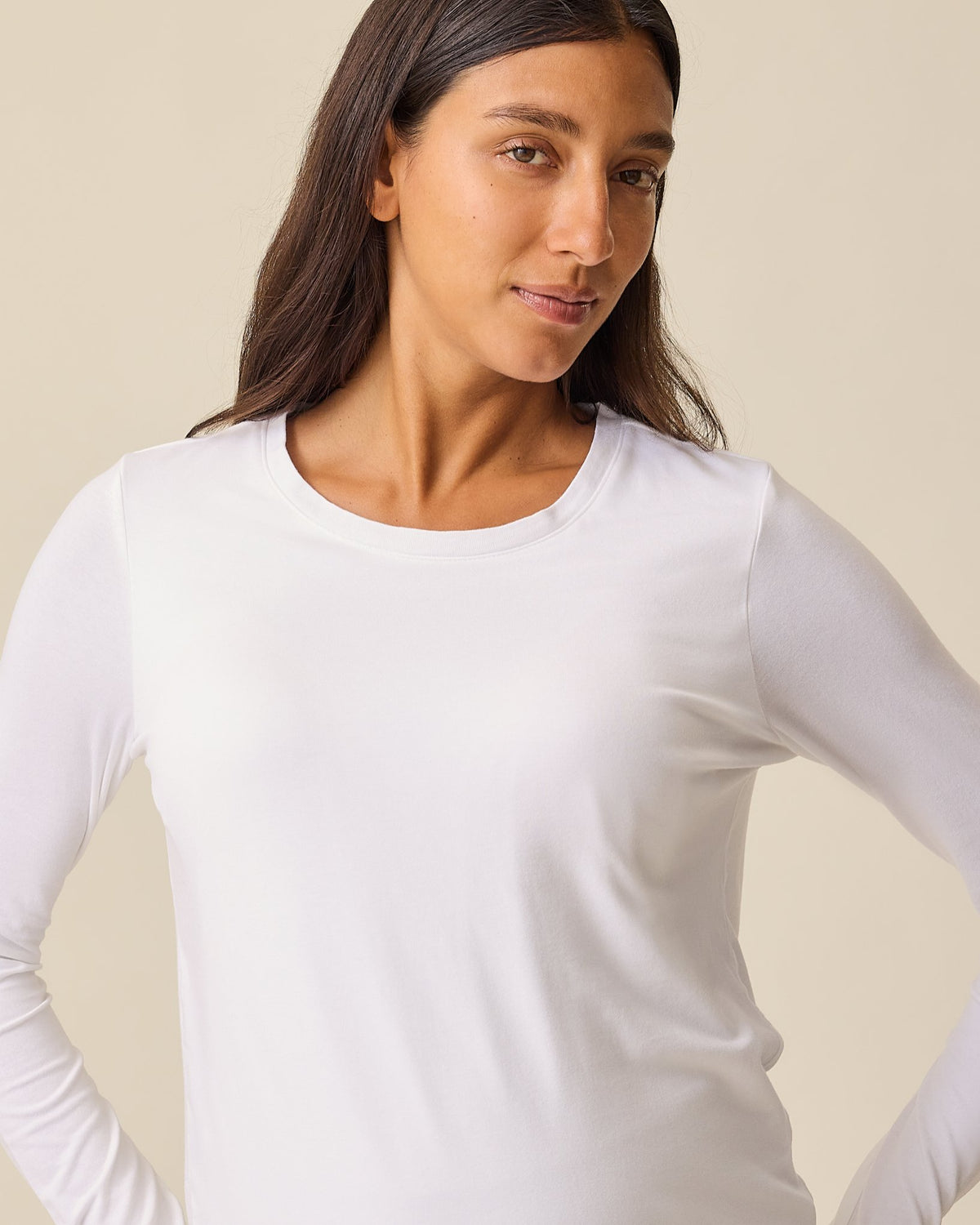 Pregnant model is wearing Modal Long Sleeve Nursing T-shirt in White on a beige background.