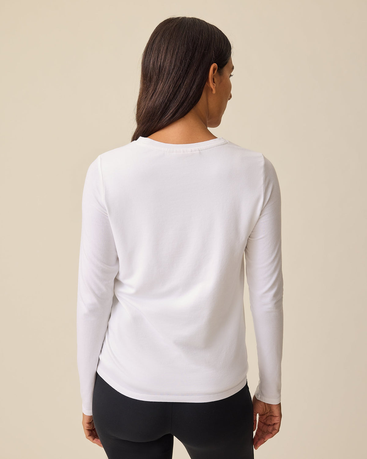 Back view of pregnant model wearing Modal Long Sleeve Nursing T-shirt in White on a beige background.