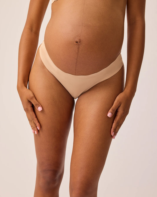 Close up of model wearing BareBond™ Cotton Maternity & Postpartum Thong in Sand on a beige background.  @model_info:Ale is wearing a Small.