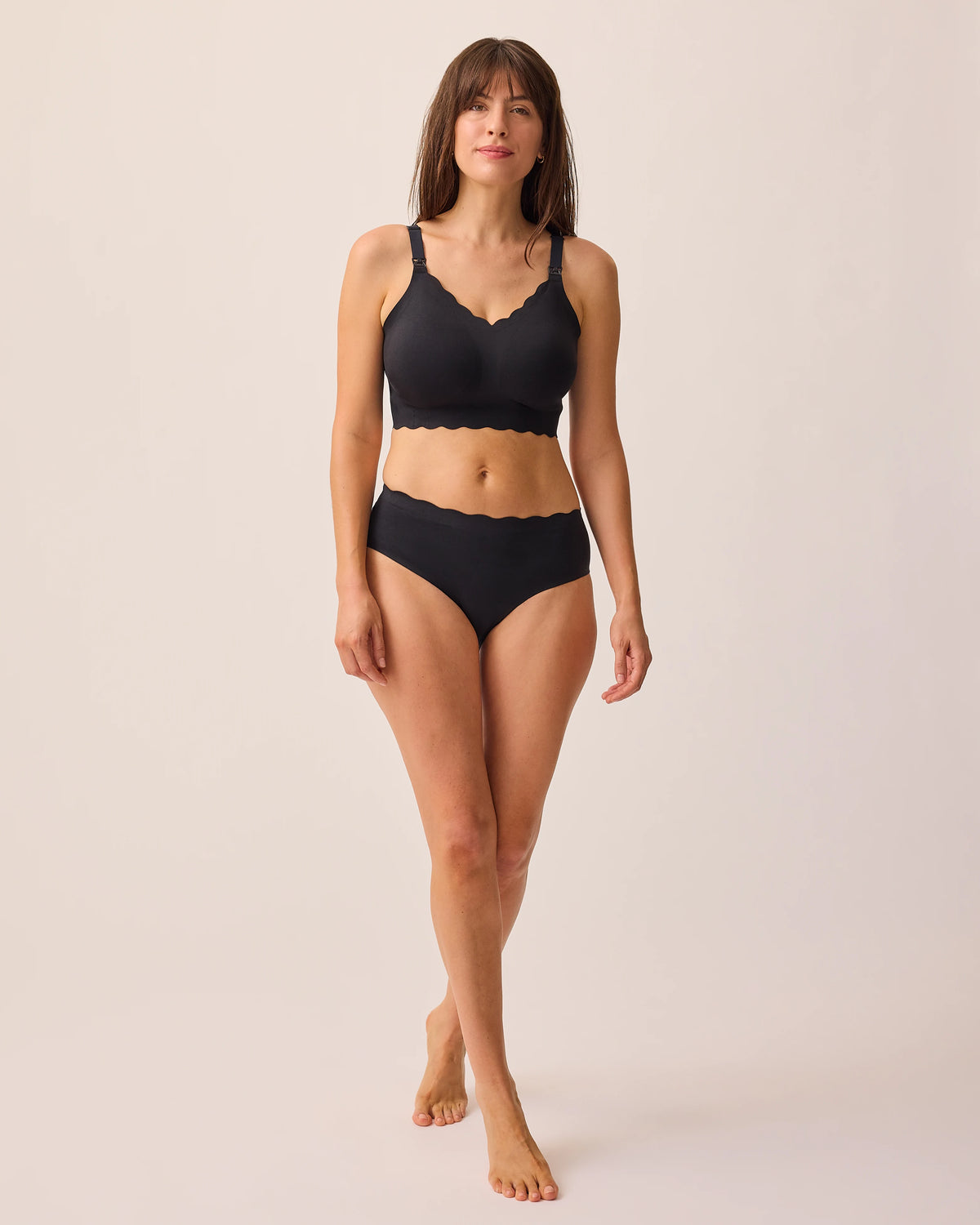 Model is wearing BareBond™ Cotton Maternity & Postpartum Brief in Black and BareBond™ Cotton Maternity & Nursing Bra in Black on a beige background.