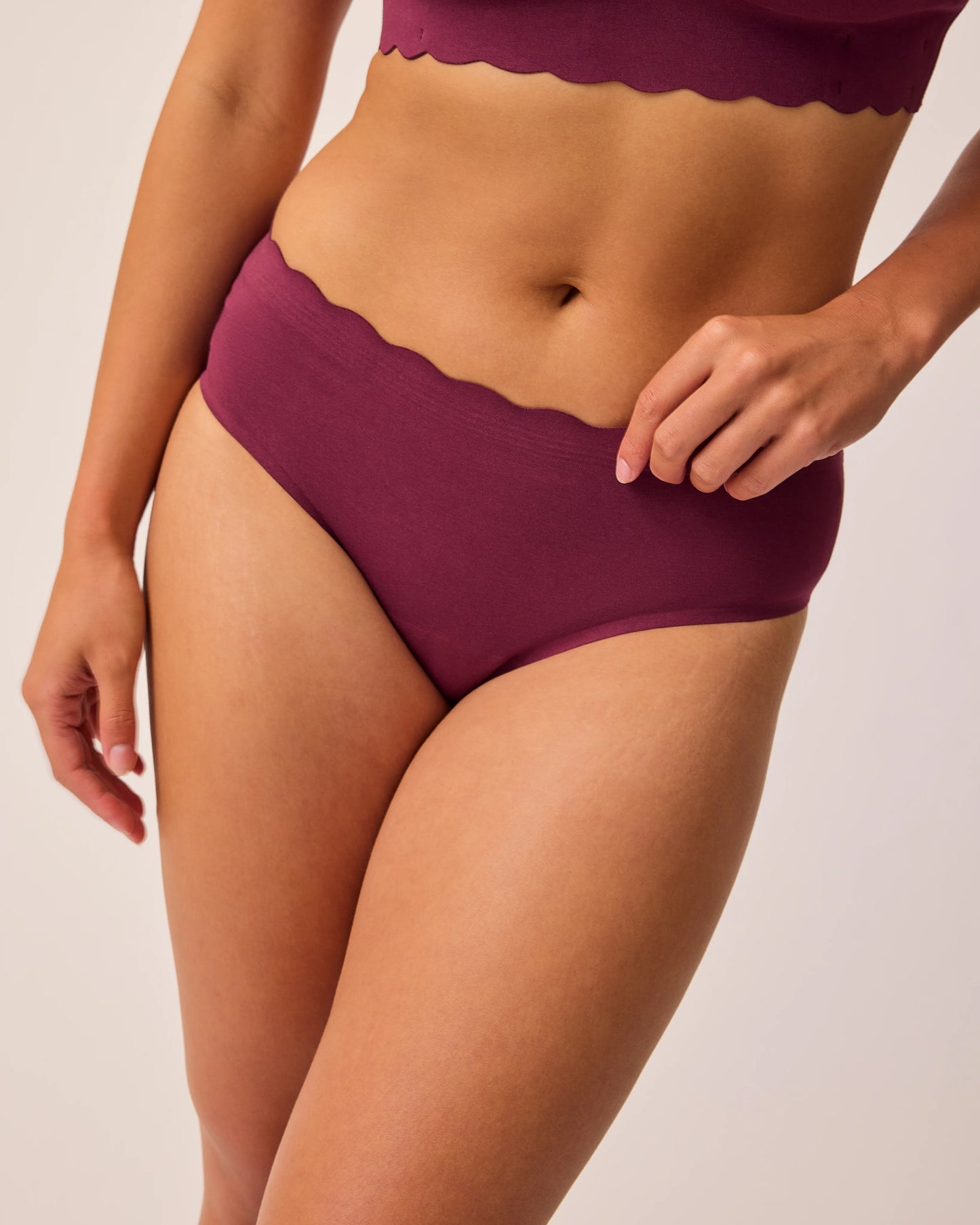 Close up of model wearing BareBond™ Cotton Maternity & Postpartum Hipster in Garnet and BareBond™ Cotton Maternity & Nursing Bra in Garnet on a beige background. @model_info:Sadie is wearing a Medium.