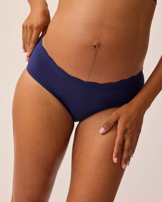 Close up of model wearing BareBond™ Cotton Maternity & Postpartum Hipster in Coastal Navy on a beige background.  @model_info:Ale is wearing a Small.