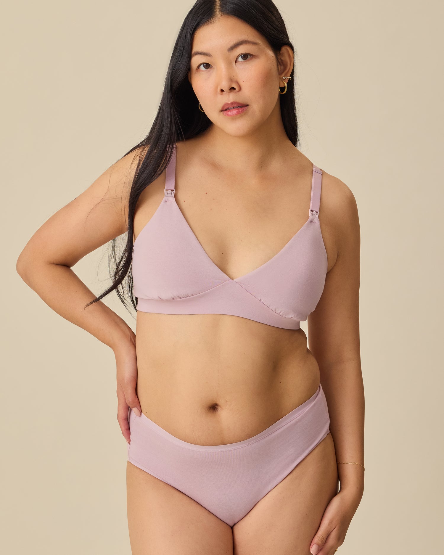 Model is wearing SoftStretch Cotton Maternity & Nursing Bralette in Lilac Mist and SoftStretch Cotton Maternity & Postpartum Hipster in Lilac Mist, on a beige background.