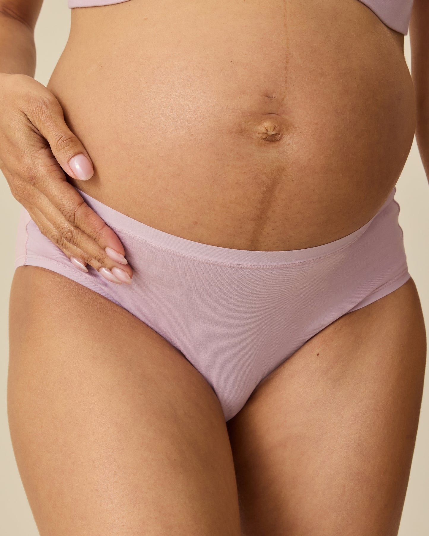 Model is wearing SoftStretch Cotton Maternity & Postpartum Hipster in Lilac Mist, on a beige background.@model_info:Courtney is wearing a Small.