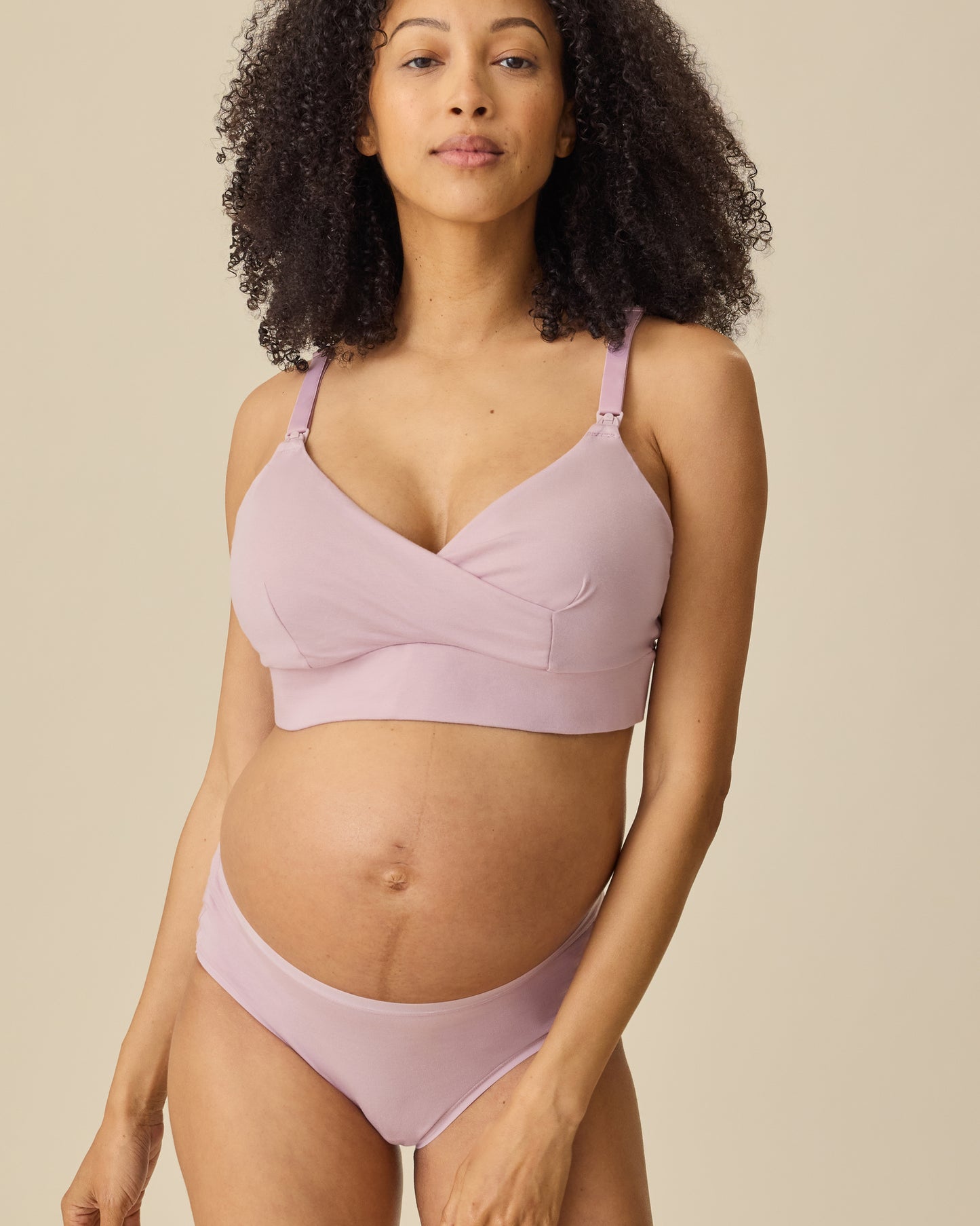 Model is wearing SoftStretch Cotton Nursing Bra in Lilac Mist and SoftStretch Cotton Maternity & Postpartum Hipster in Lilac Mist, on a beige background.