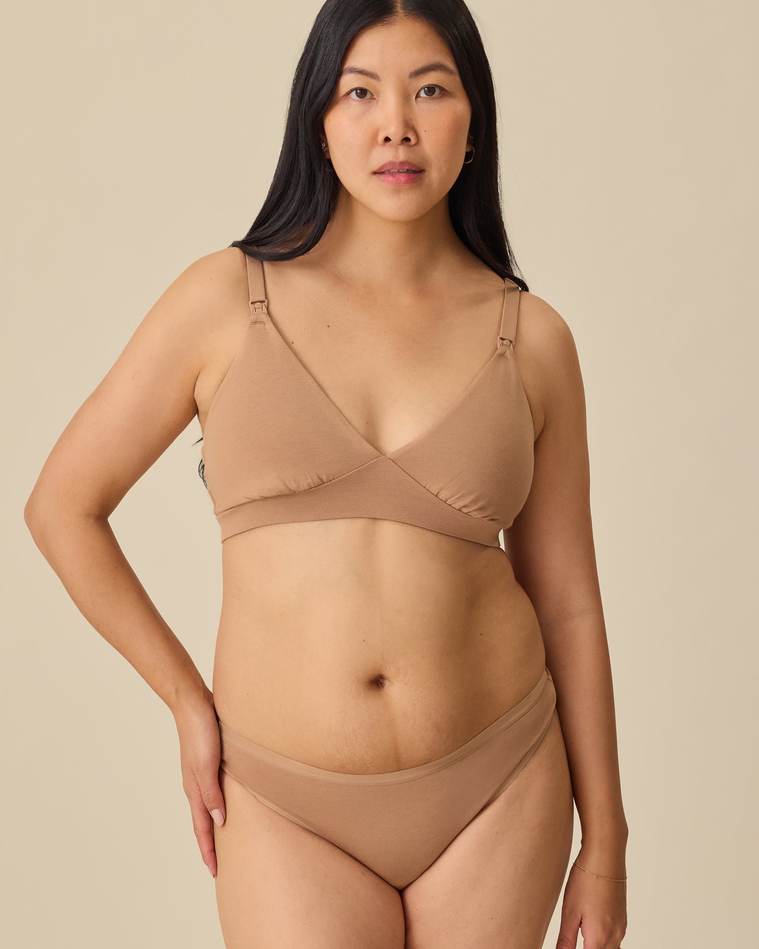 Model is wearing the SoftStretch Cotton Maternity & Nursing Bralette in Buff and SoftStretch Cotton Maternity & Postpartum Thong in Buff, on a beige background.
