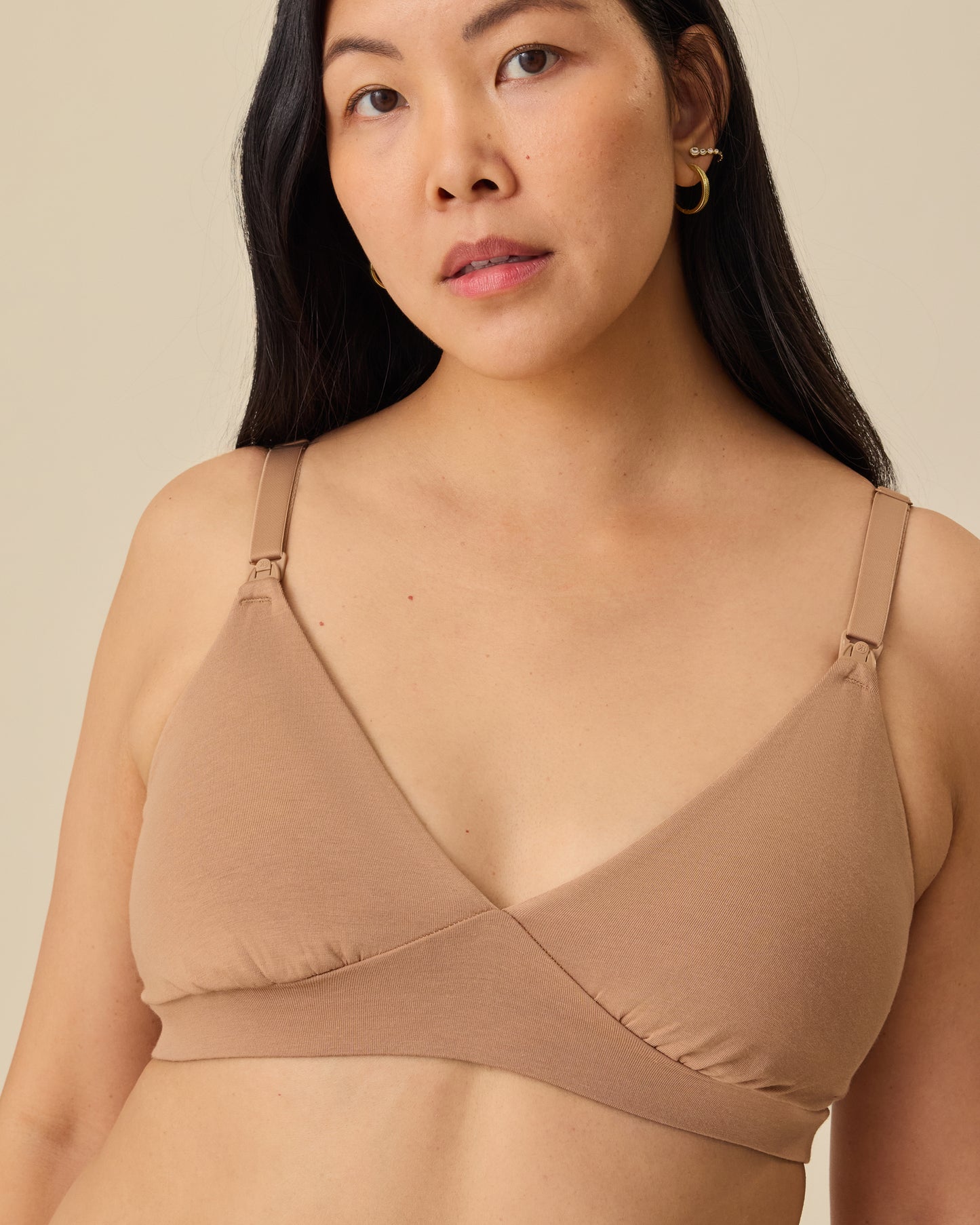 Model is wearing the SoftStretch Cotton Maternity & Nursing Bralette in Buff, on a beige background. @model_info:Theresa is wearing a Small.