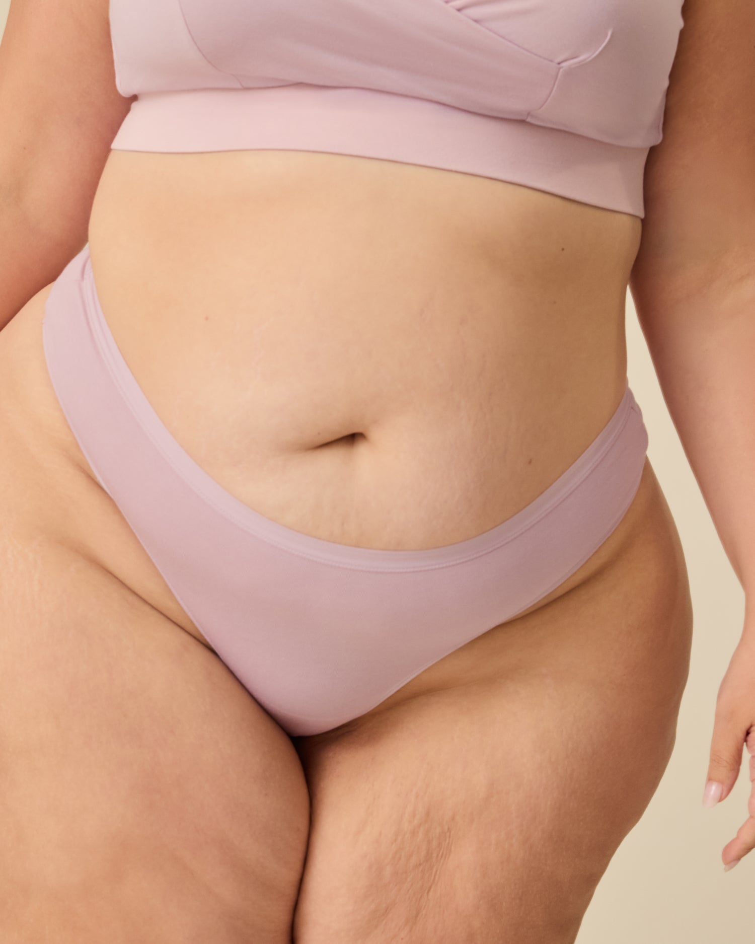 Close up of Model wearing SoftStretch Cotton Nursing Bra in Lilac Mist and SoftStretch Cotton Maternity & Postpartum Thong in Lilac Mist on a beige background. @model_info:Allie is wearing a 1X.