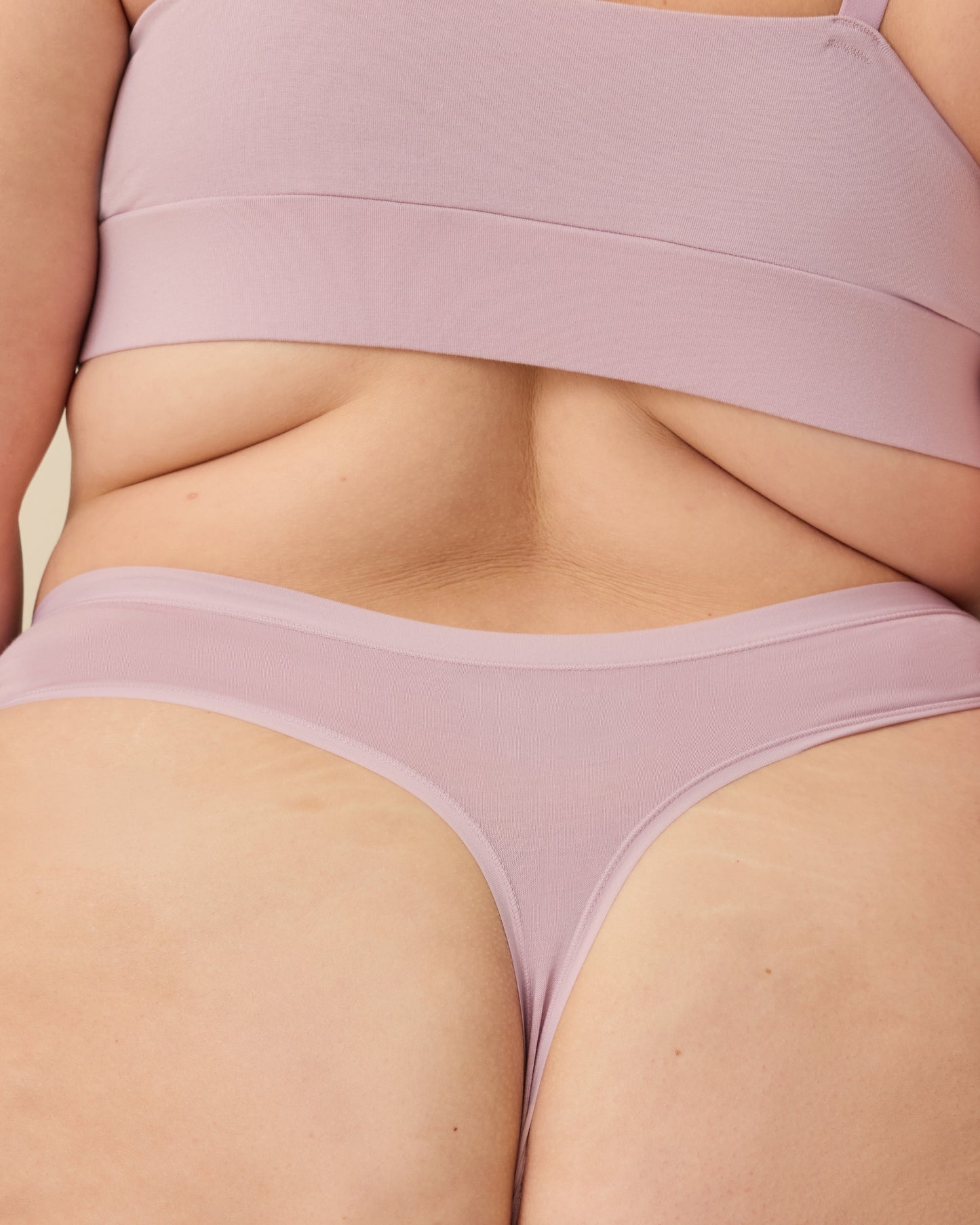 Back view of model wearing SoftStretch Cotton Nursing Bra in Lilac Mist and SoftStretch Cotton Maternity & Postpartum Thong in Lilac Mist on a beige background.