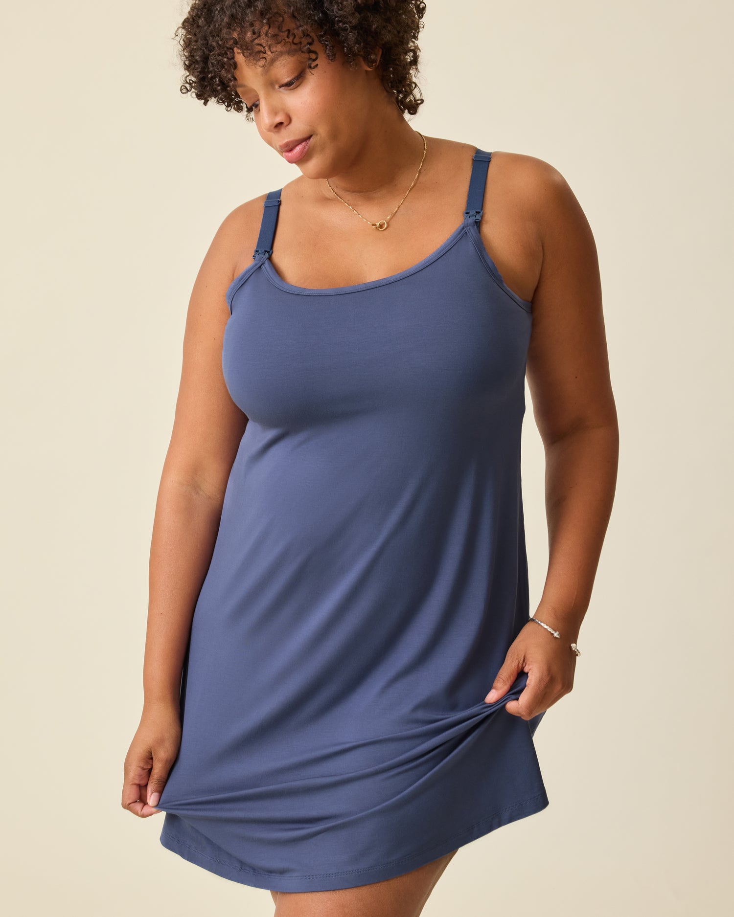 Model is wearing Stella Hands-Free Pumping & Nursing Nightgown in Slate Blue, on a beige background.