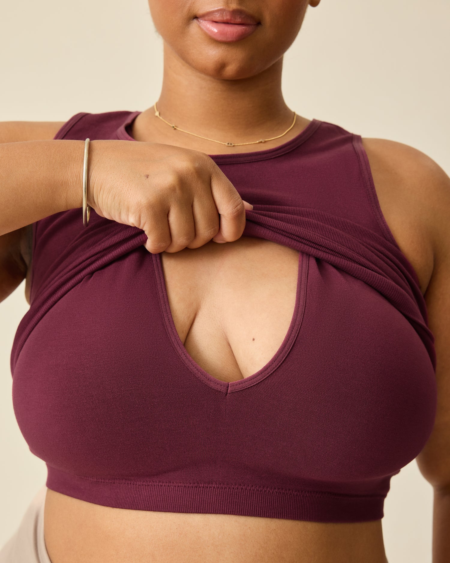Model is lifting nursing panel on the Sublime® Bamboo Maternity & Nursing Longline Bra Top in Deep Burgundy on a beige background.