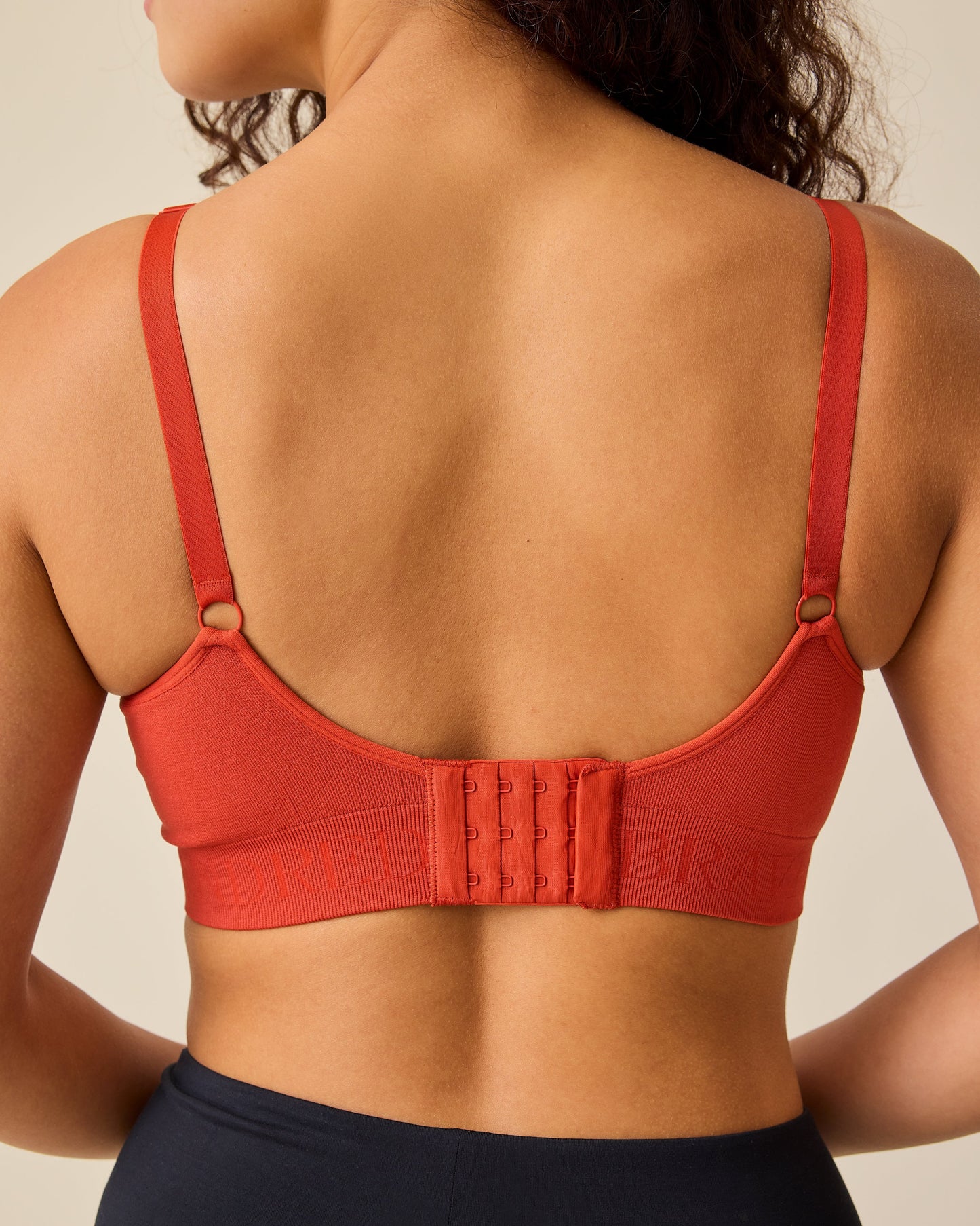 Back view of the model wearing Simply Sublime® Nursing Bra in Spice on a beige background. 
