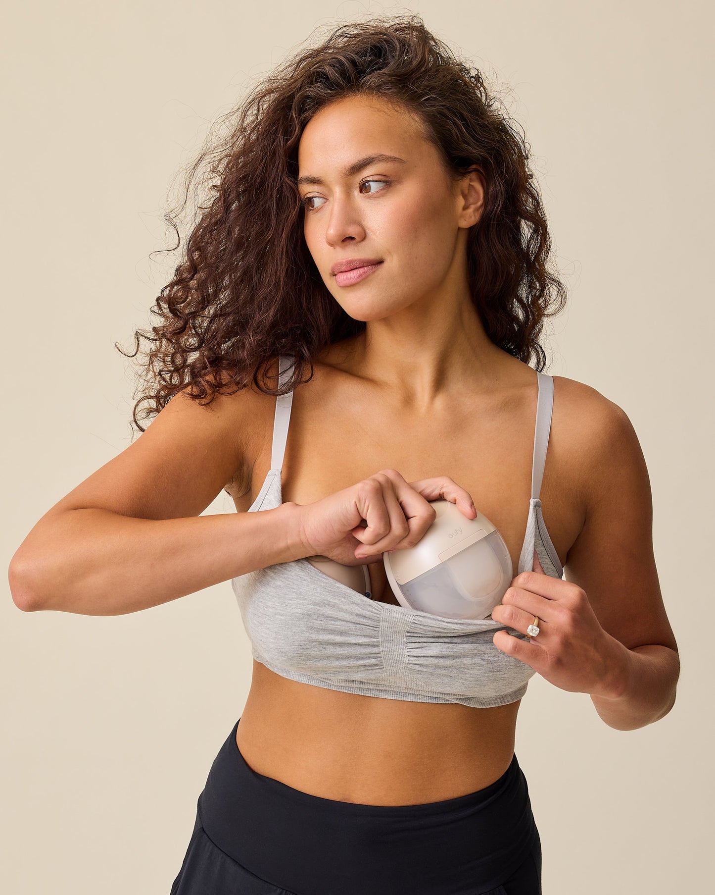 Model is inserting pumps while wearing Sublime® Bamboo Hands-Free Pumping Lounge & Sleep Bra in Grey Heather on a beige background.
