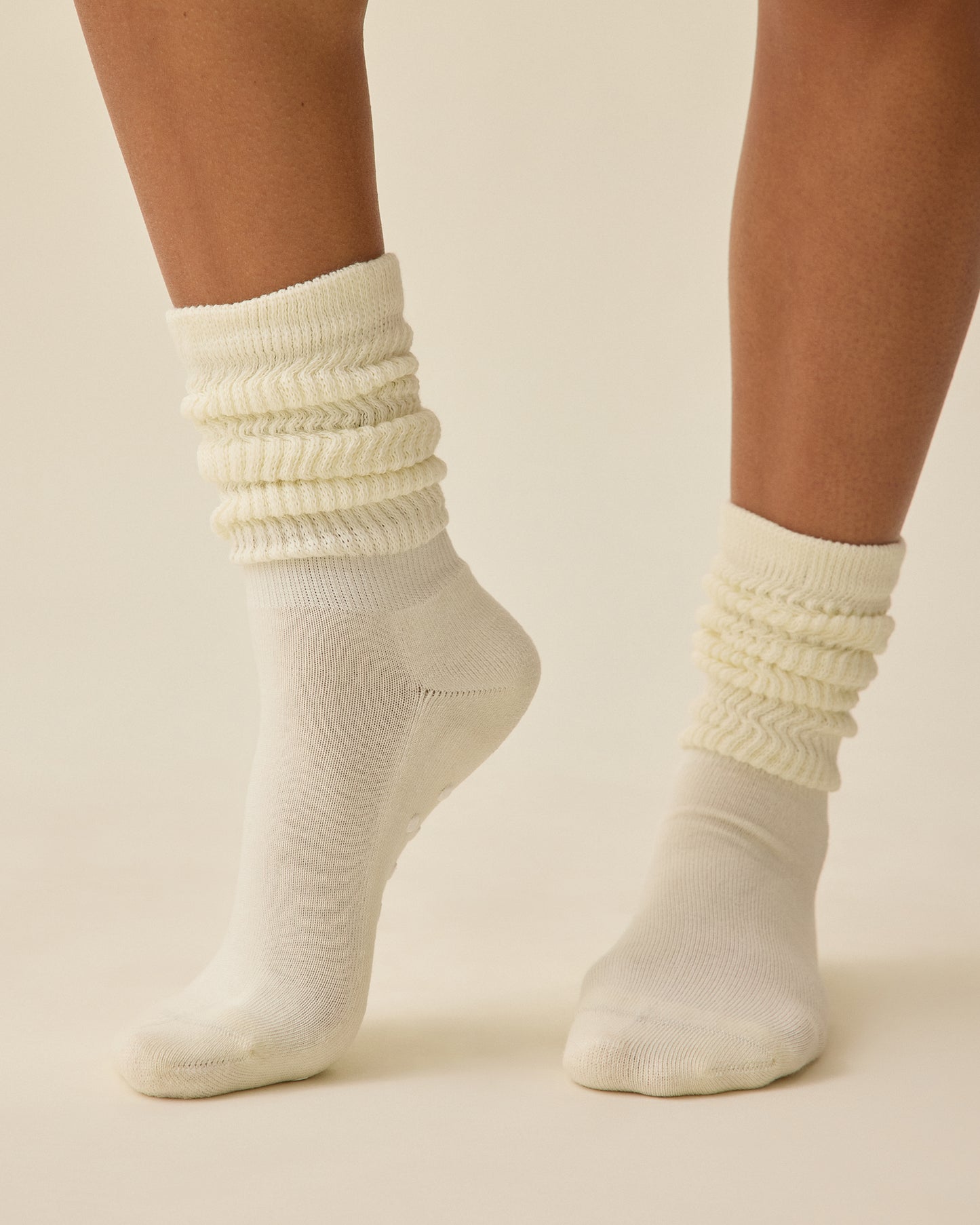 Model is wearing a pair of Non-Slip Slouchy Socks in Cream on a beige background.