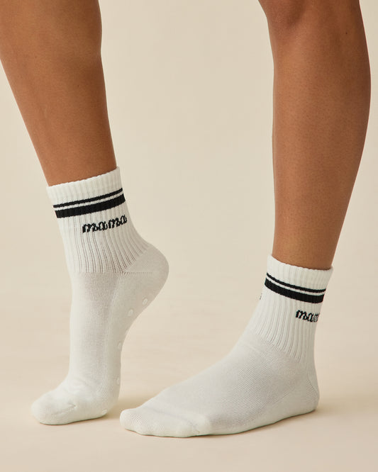 Model is wearing a pair of Non-Slip Quarter Crew Socks in Ivory & Black on a beige background.