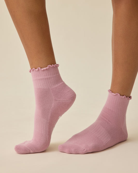 Model is wearing a pair of Non-Slip Ruffle Ankle Socks in Light Mauve on a beige background