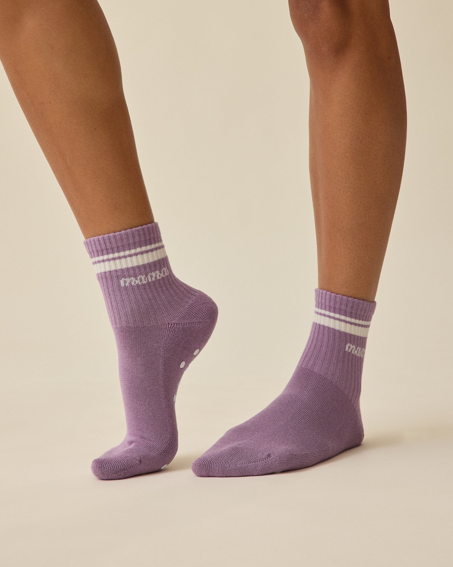 Model is wearing a pair of Non-Slip Quarter Crew Socks in Dusty Mauve & Ivory on a beige background.