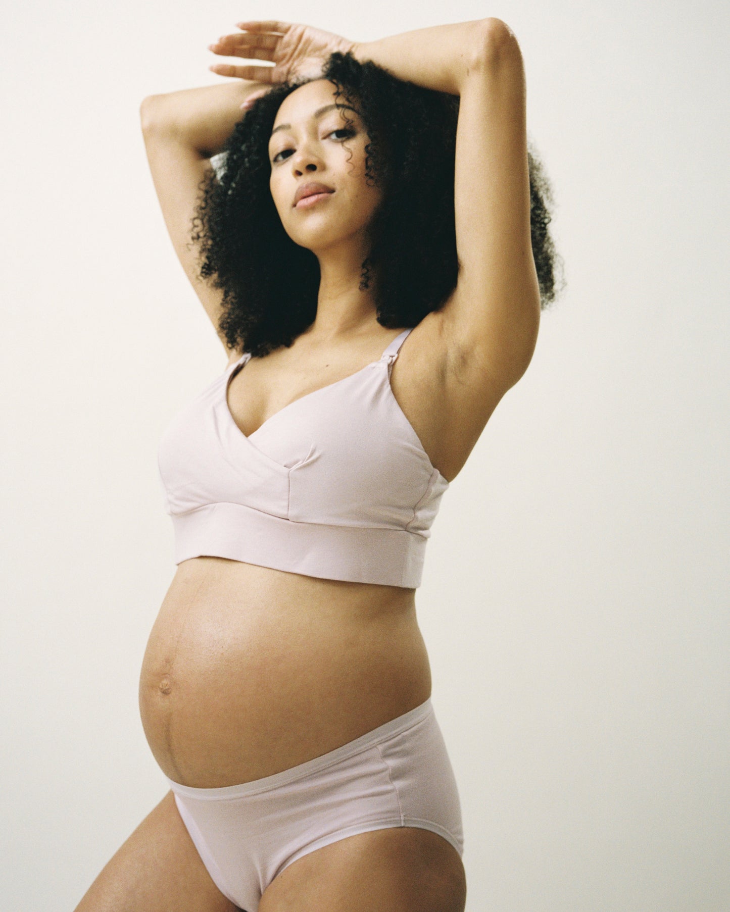 Blown out stylized image of Pregnant model wearing SoftStretch Cotton Nursing Bra and SoftStretch Cotton Maternity & Postpartum Brief in Lilac Mist on a beige background.