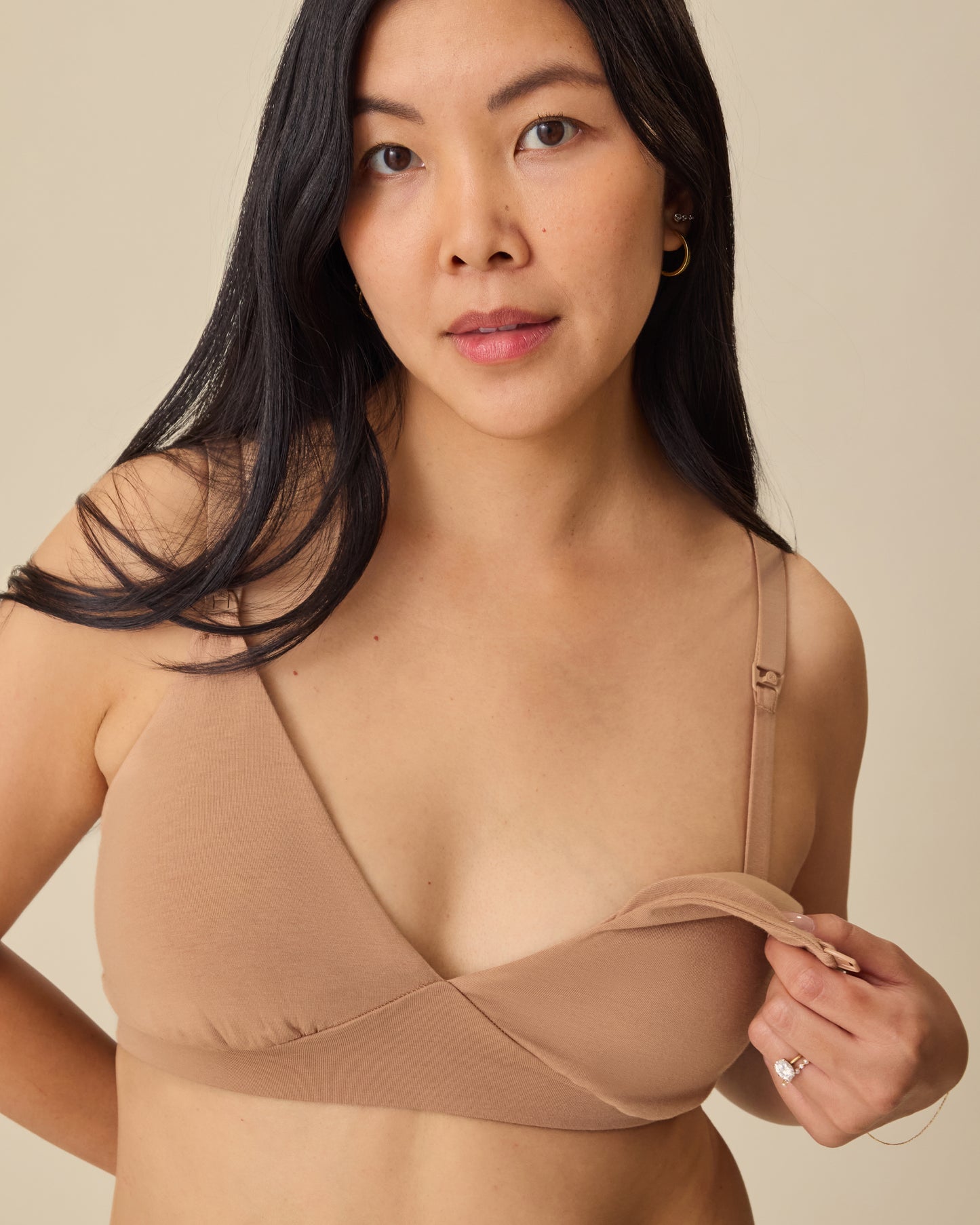 Model is showing the easy nursing access on the SoftStretch Cotton Maternity & Nursing Bralette in Buff, on a beige background. 