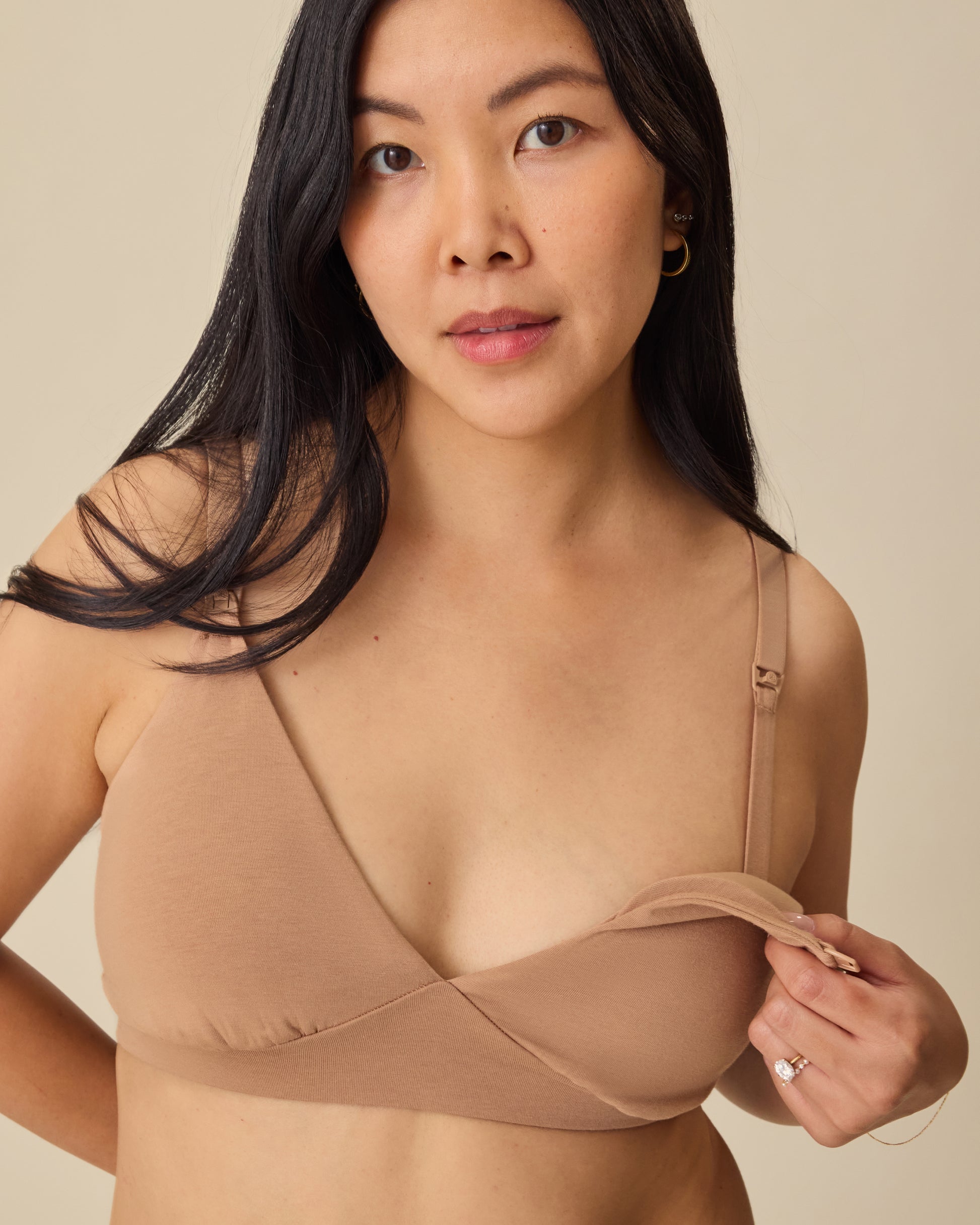 Model is showing the easy nursing access on the SoftStretch Cotton Maternity & Nursing Bralette in Buff, on a beige background. 