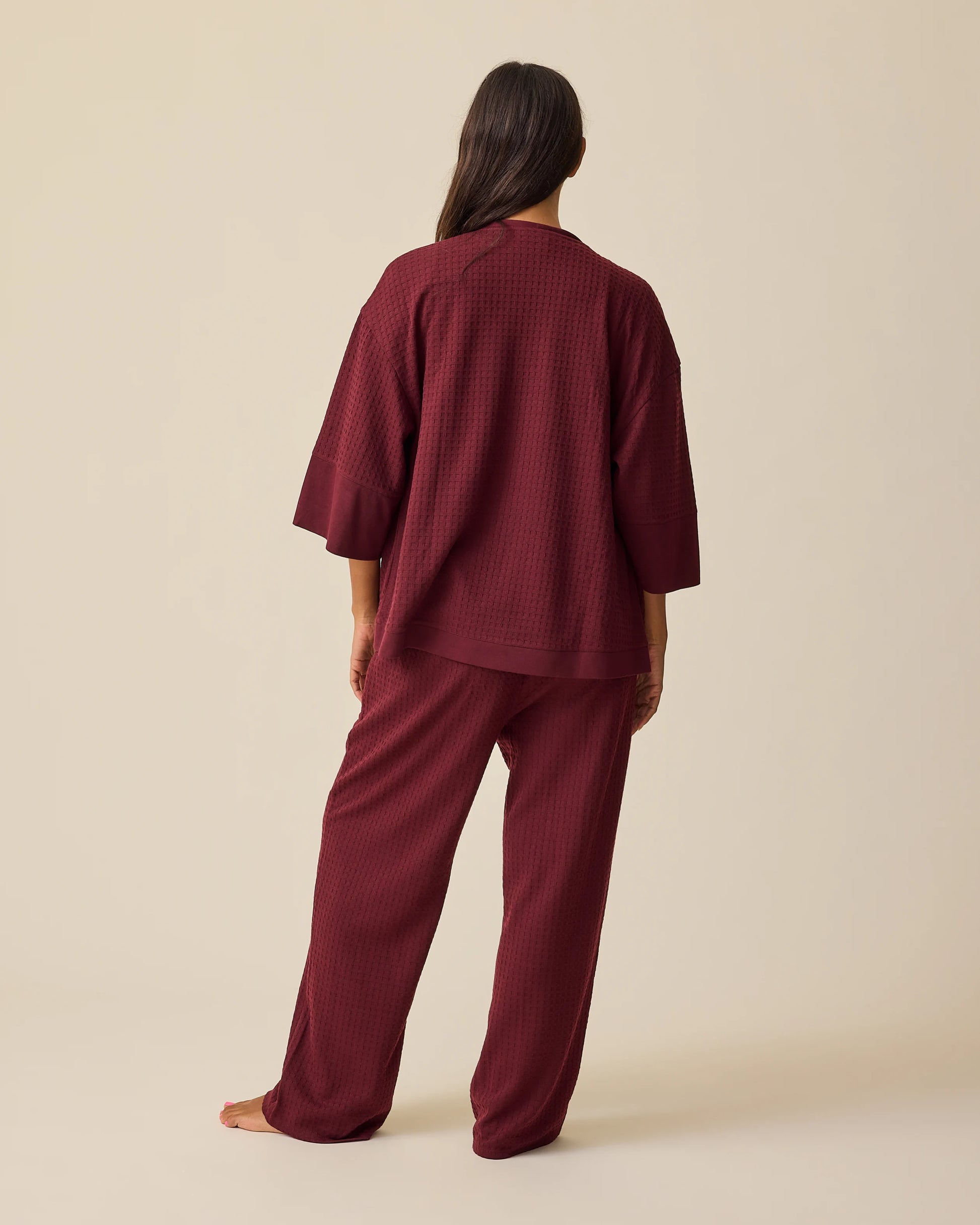 Back view of model wearing Waffle Maternity & Nursing Three-Piece Lounge Set in Garnet on a beige background.