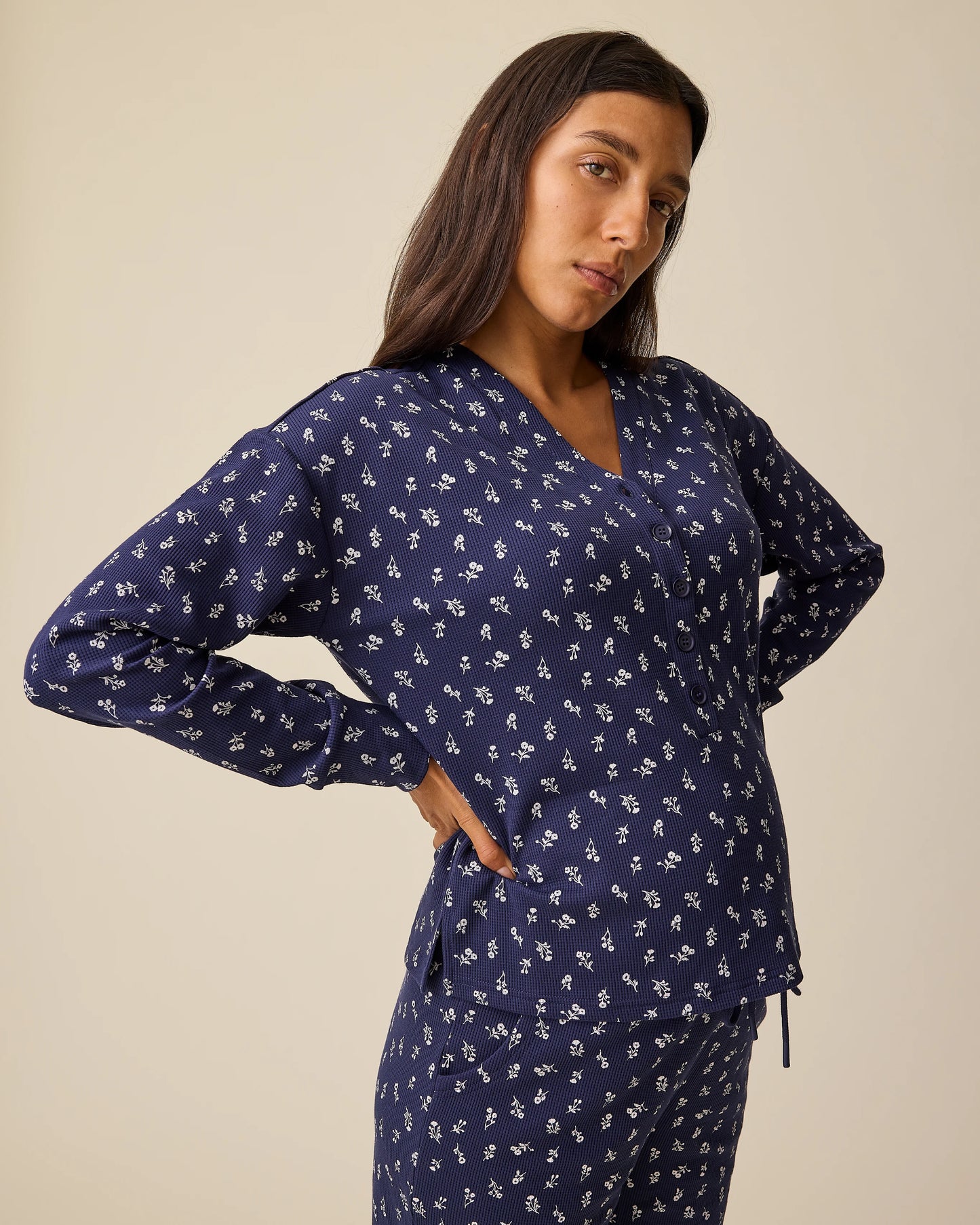 Angled view of model wearing Waffle Maternity & Nursing Lounge Set in Navy Wildflower on a beige background.
