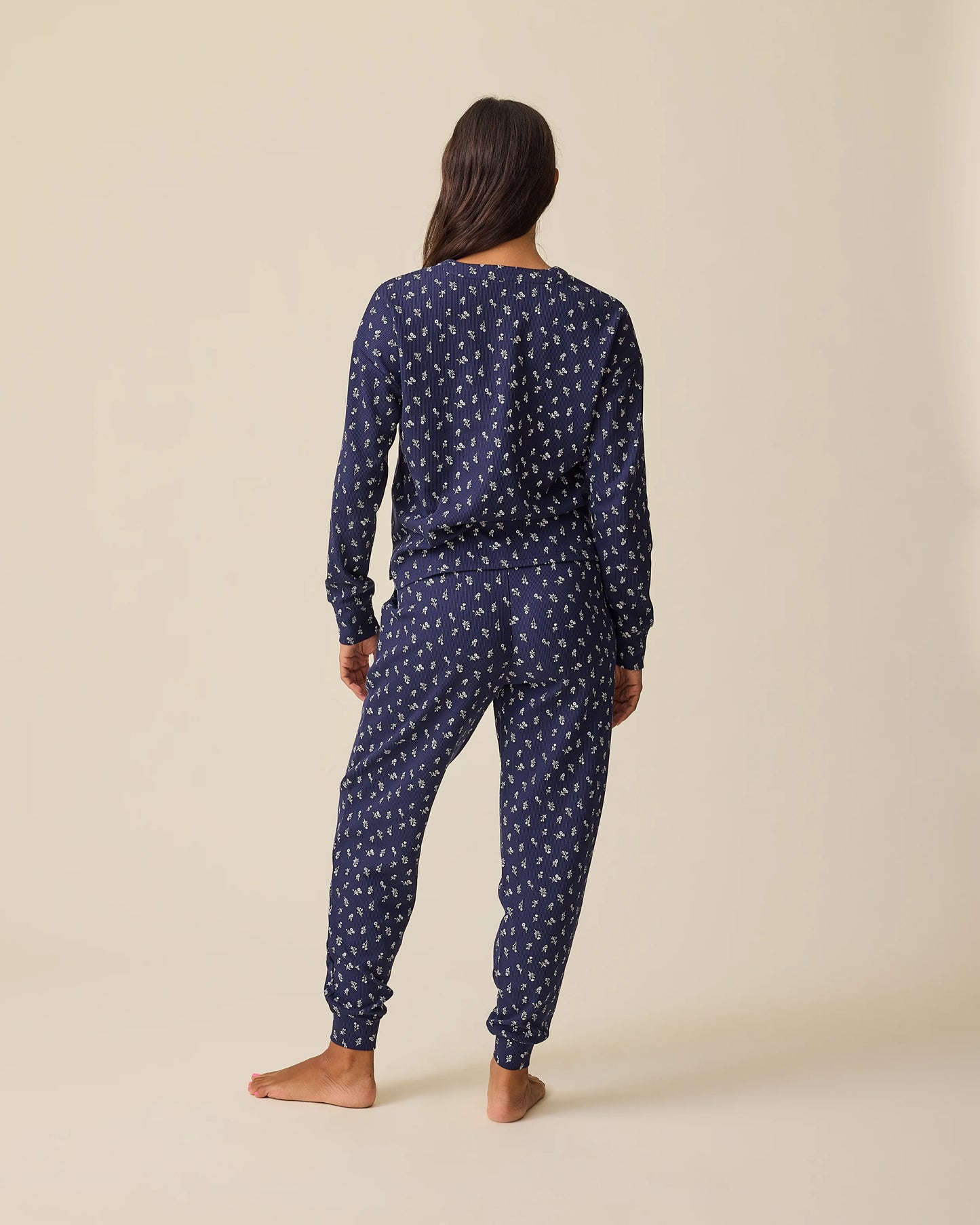 Back view of model wearing Waffle Maternity & Nursing Lounge Set in Navy Wildflower on a beige background.
