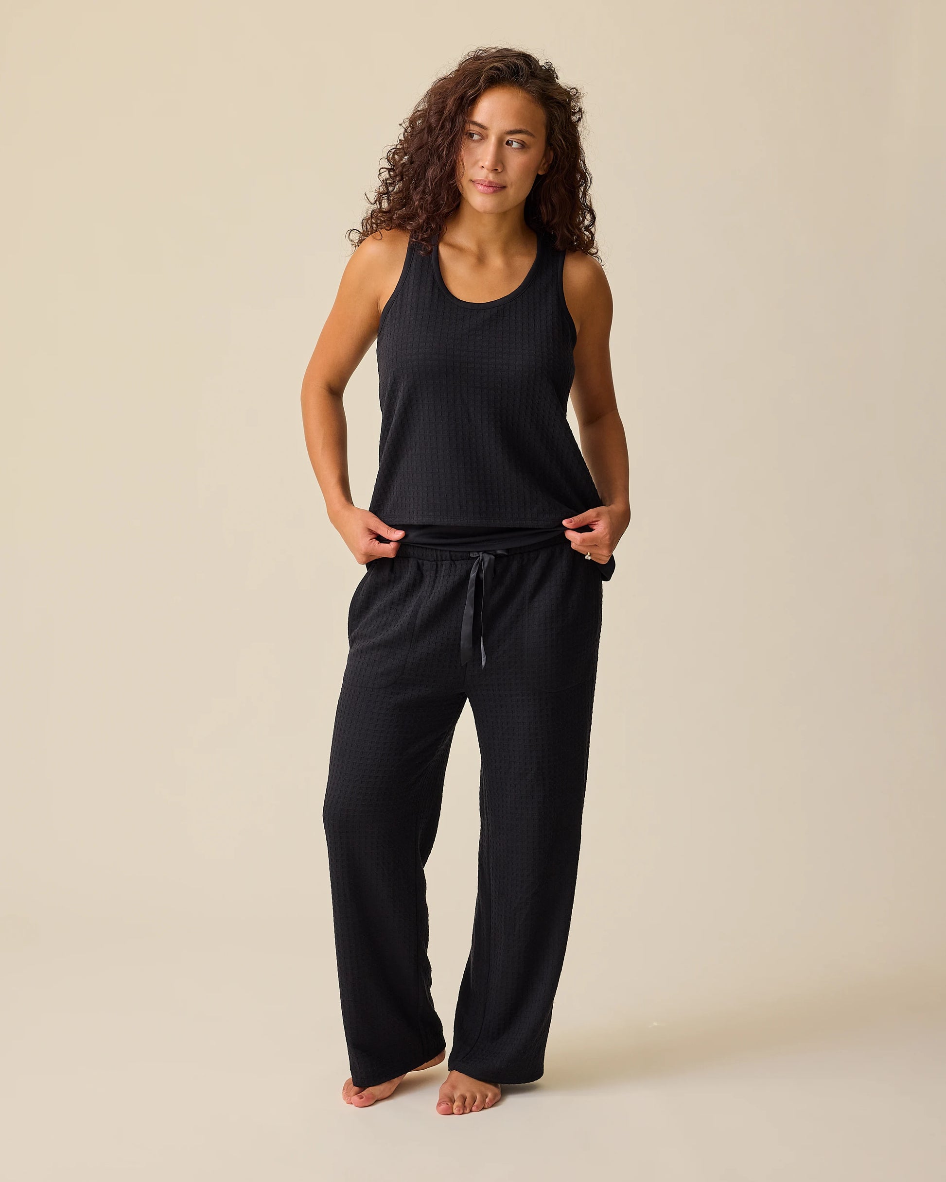 Model is wearing two of the three pieces of the Waffle Maternity & Nursing Three-Piece Lounge Set in Black on a beige background.
