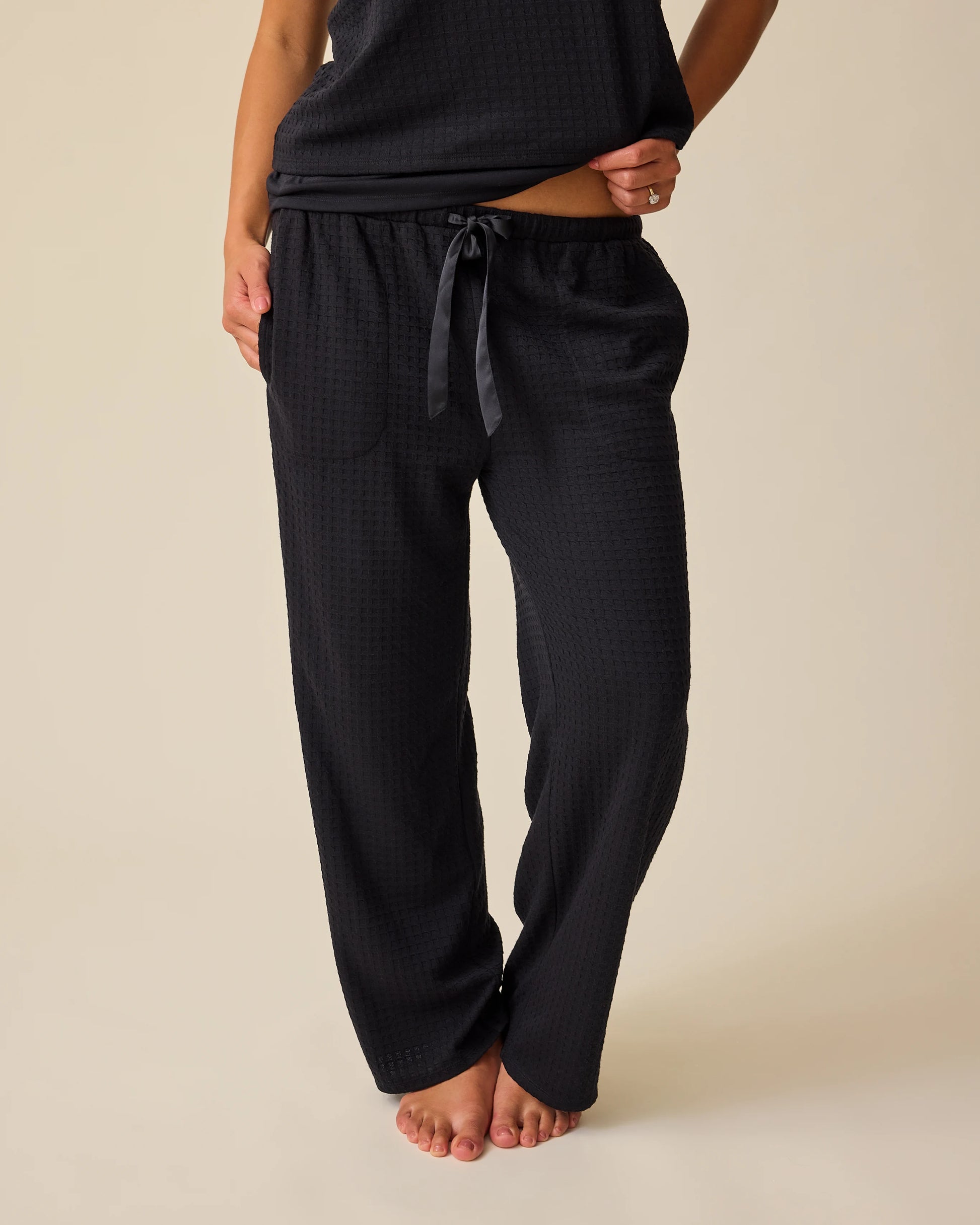 Model is wearing two of the three pieces of the Waffle Maternity & Nursing Three-Piece Lounge Set in Black on a beige background.