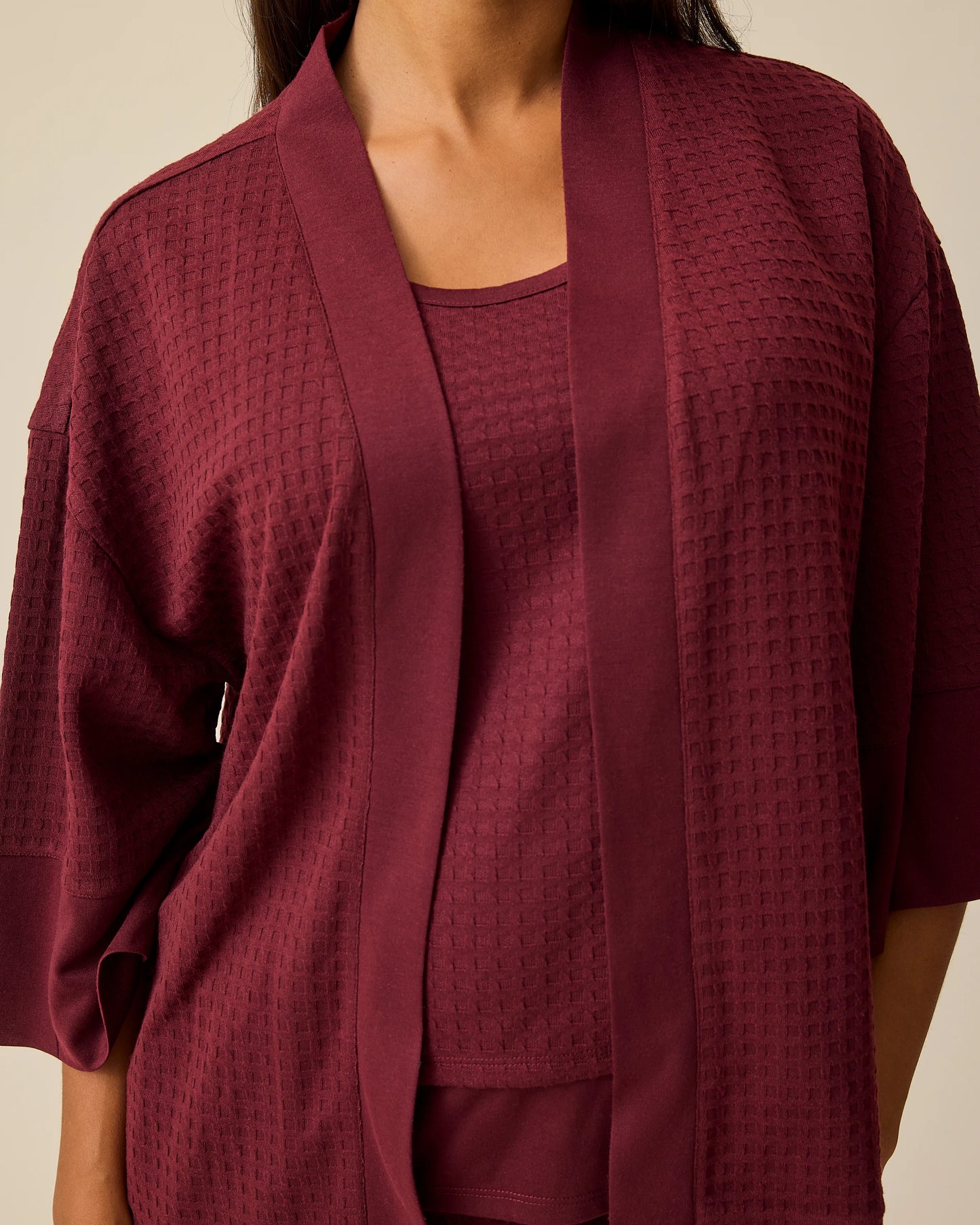 Close up of model wearing Waffle Maternity & Nursing Three-Piece Lounge Set in Garnet on a beige background.