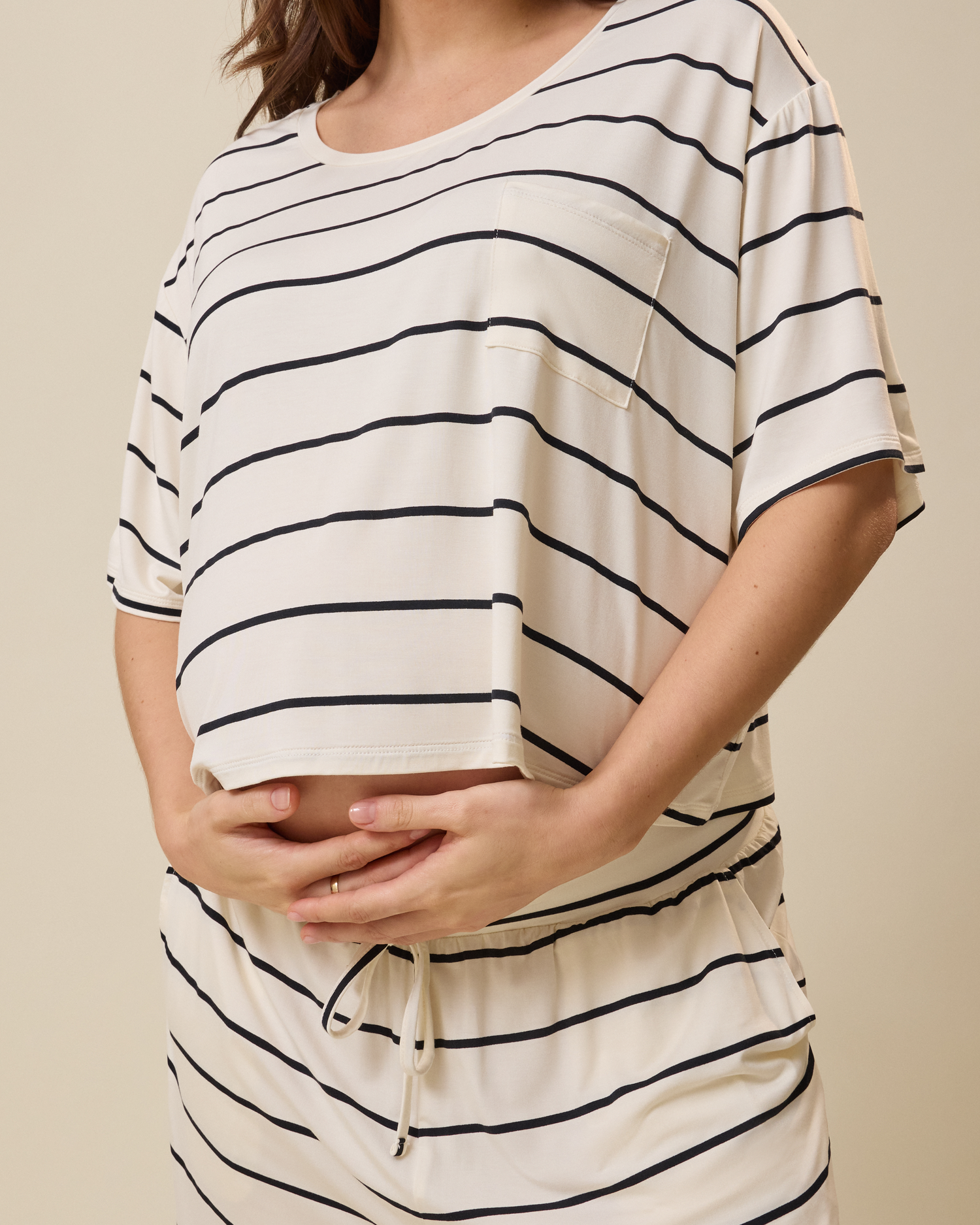 Person wearing a white and black striped lounge set on a beige background