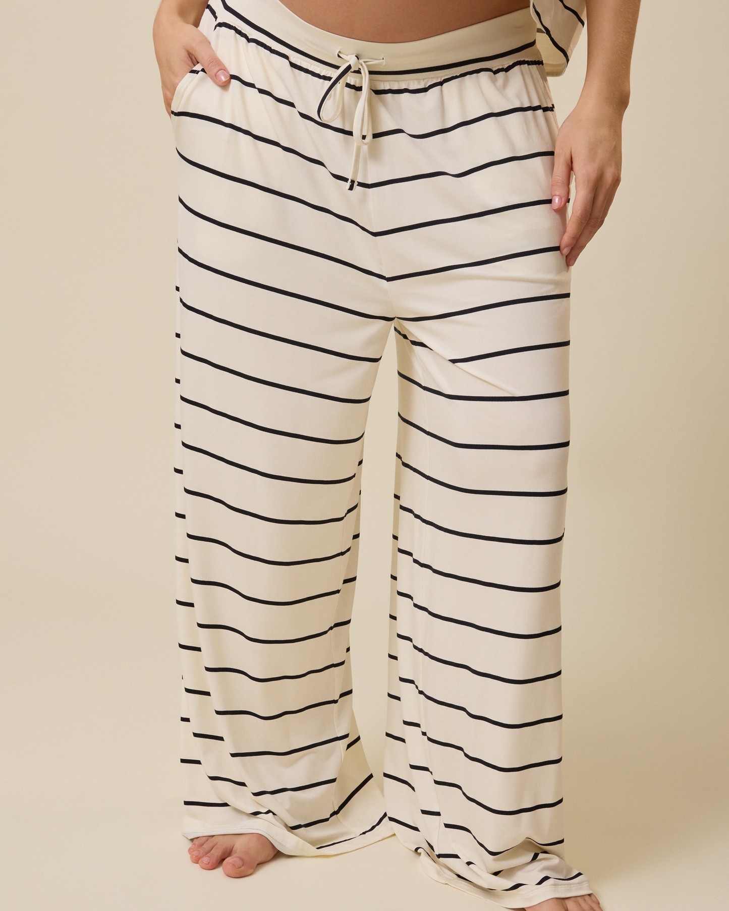 Striped lounge pajama pants worn by a person on a beige background @model_info:KJ is 5'9" and wearing a Medium.